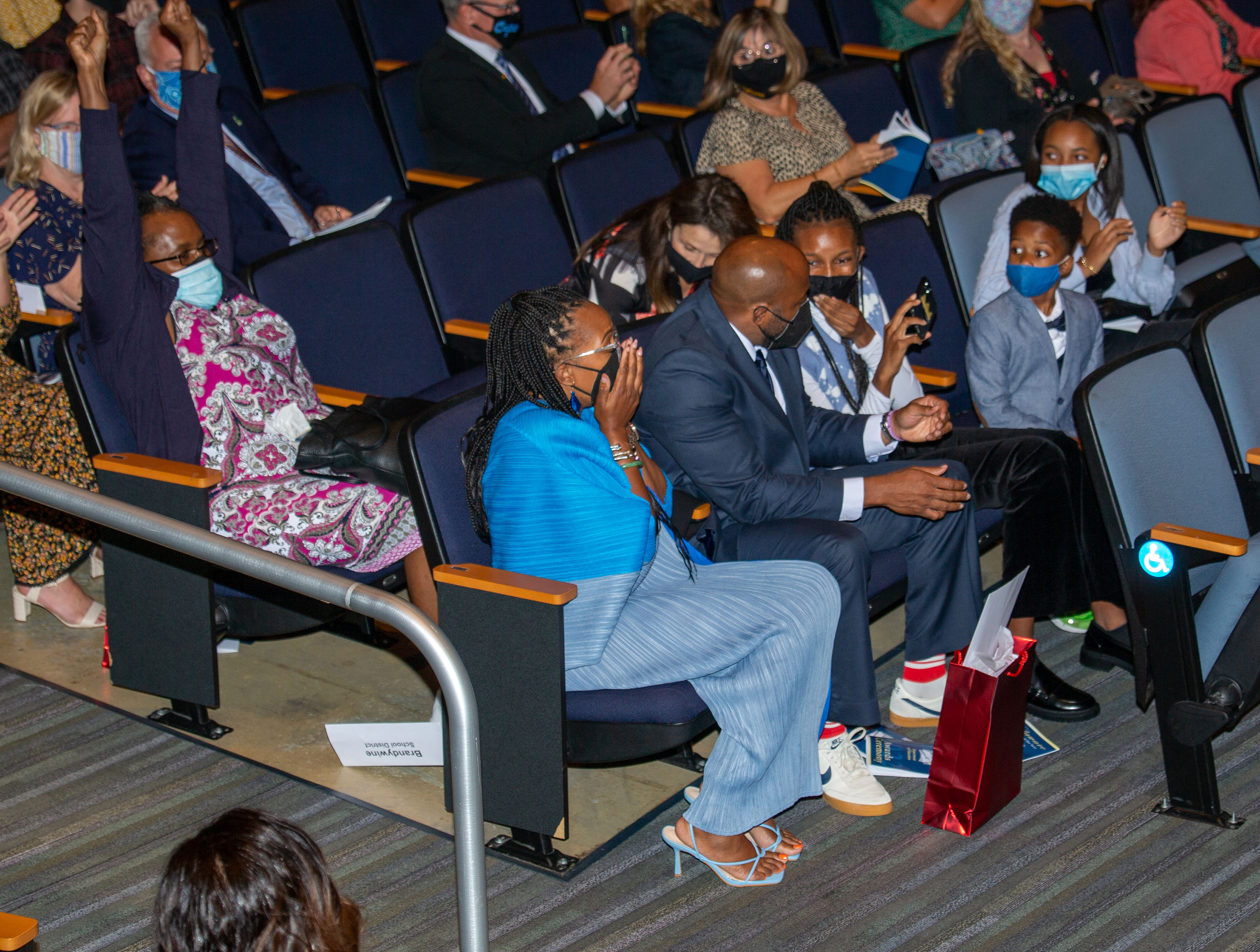 Jahsha Tabron (in blue) and her family react with surprise when her name is announced as the 2022 Del. Teacher of the Year.