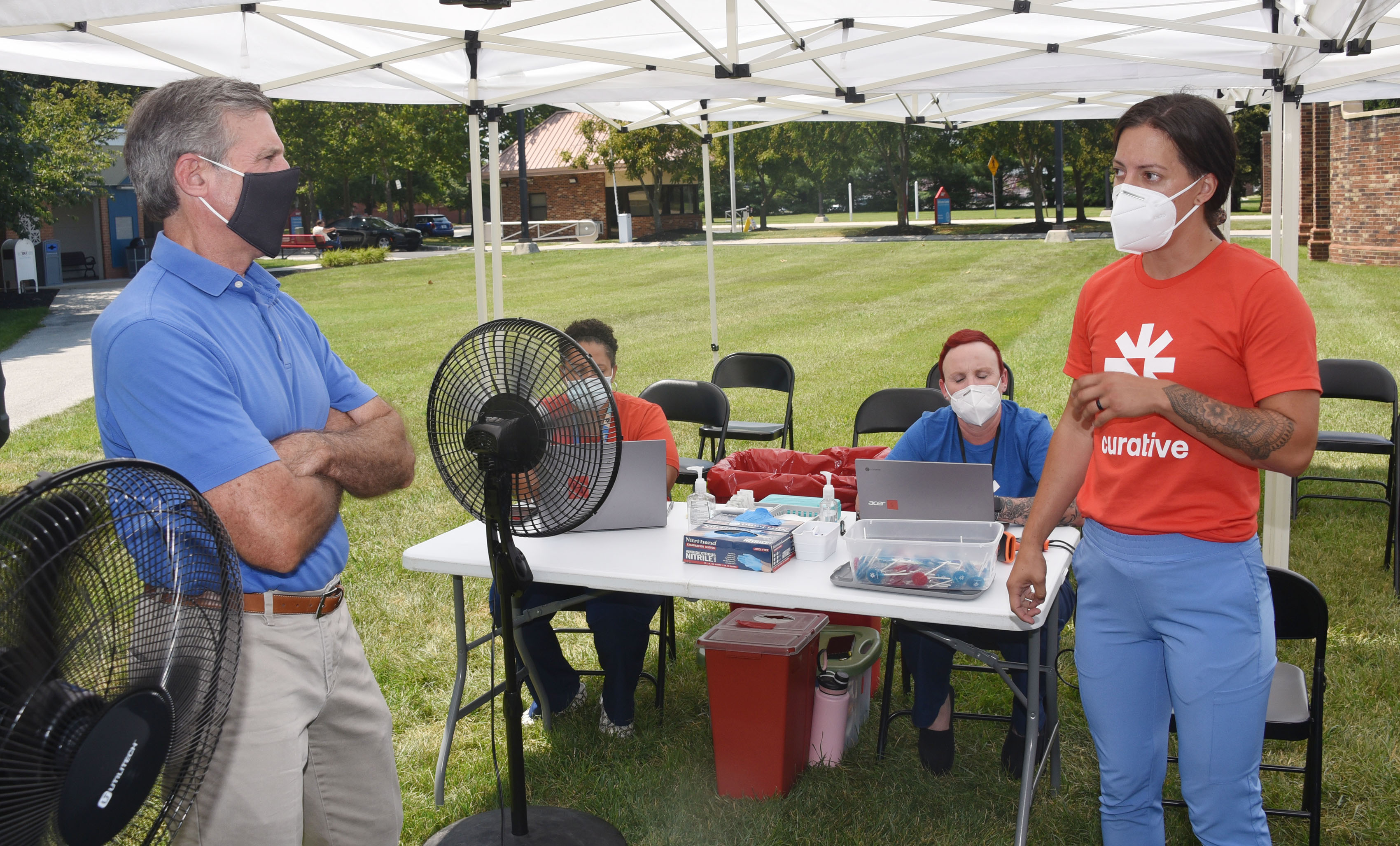 Gov. John Carney talks with volunteers at the Del State vaccination site.