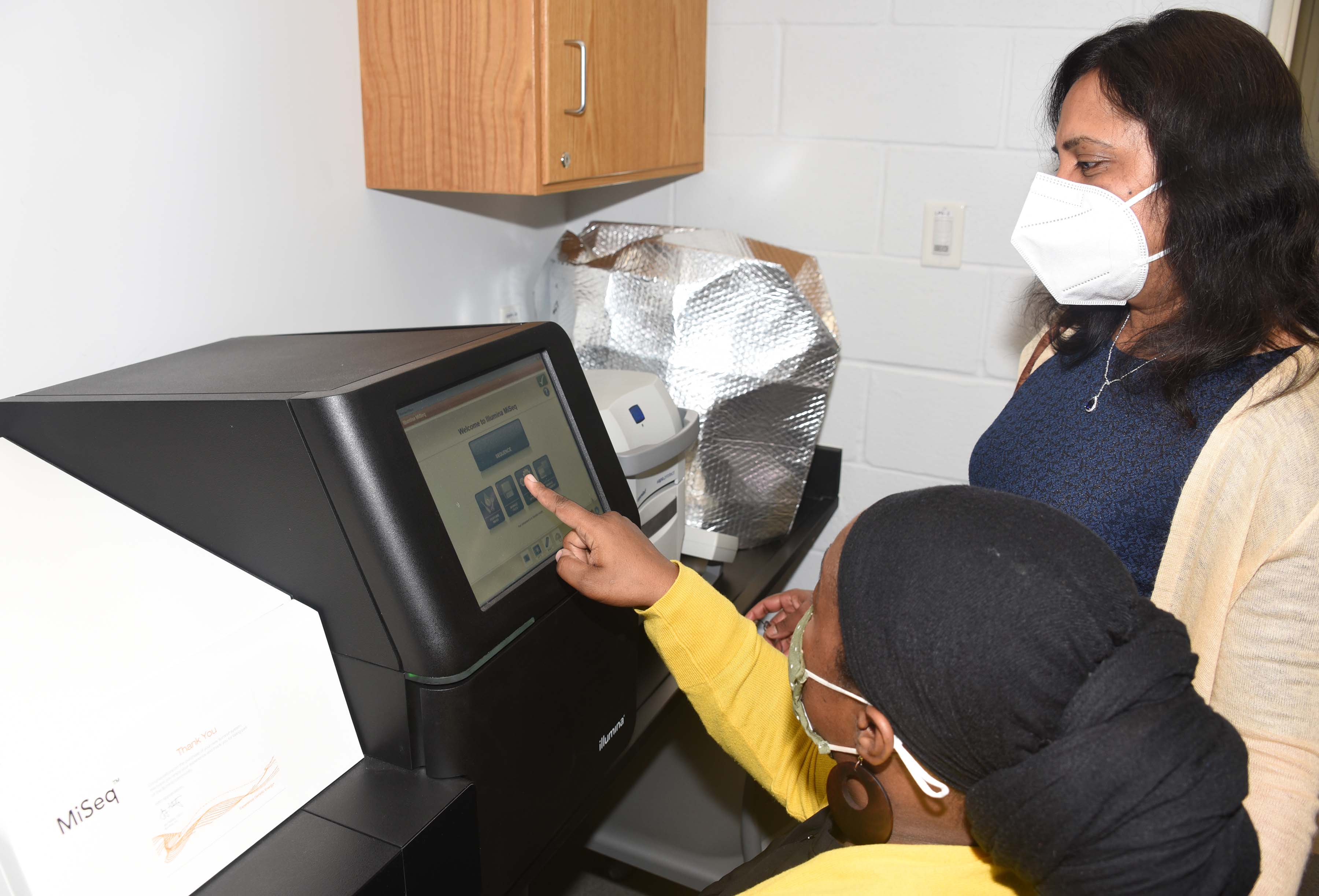 Dr. Antonette Todd and Dr. Kalpalatha Melmaiee with an Illumina Sequencer.