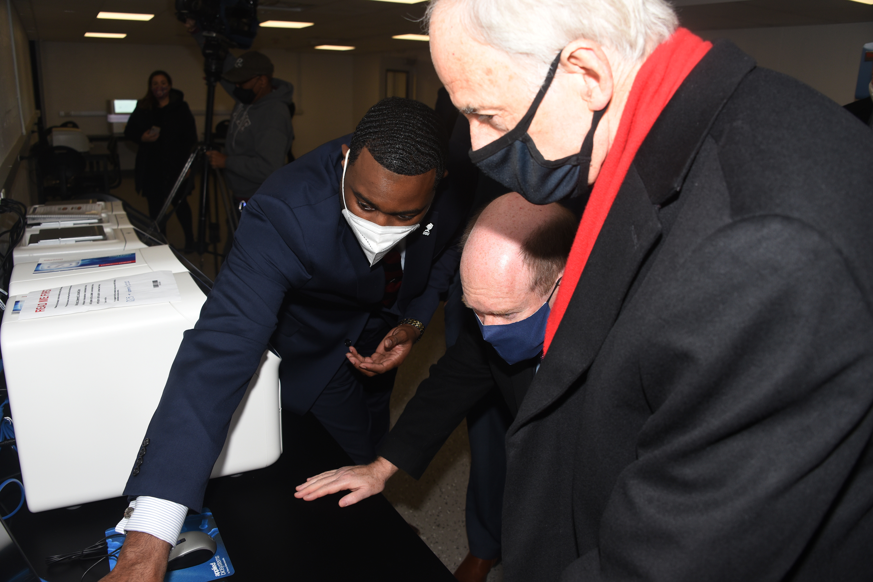 Dr. Derrick Scott, Diagnostic Lab exec. director, shows U.S. Senators Tom Carper and Chris Coons how the tests are analyzed.