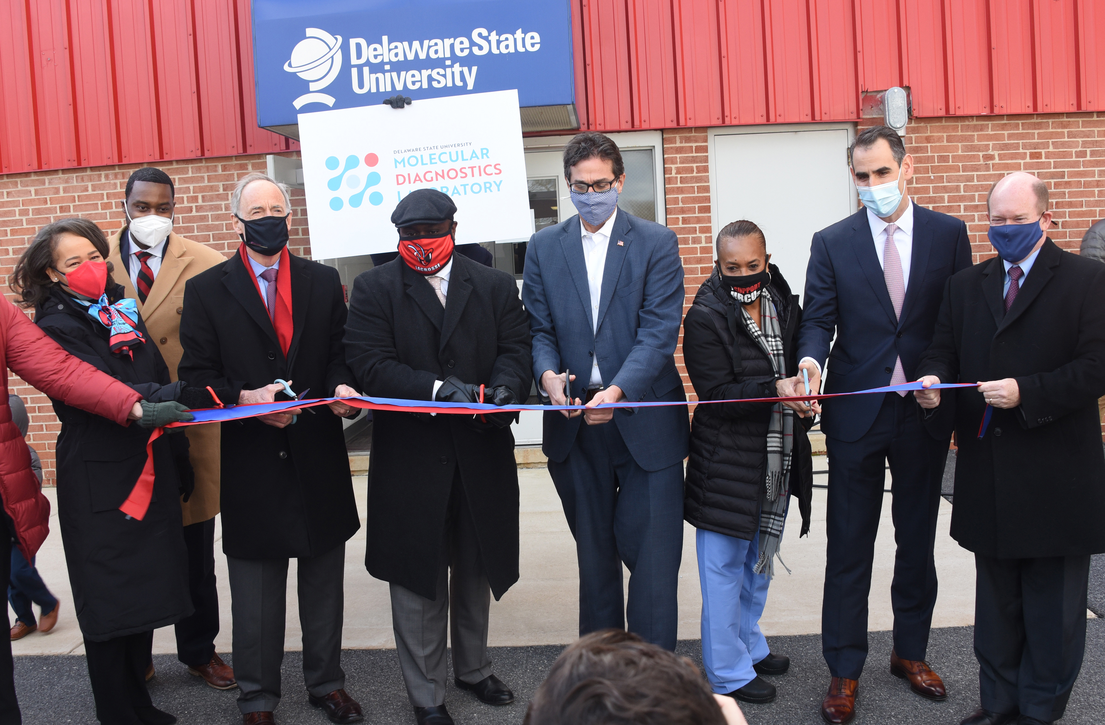 (L-r) U.S. Rep. Lisa Blunt Rochester, Dr. Derrick Scott, U.S, Sen. Tom Carper, University President Tony Allen, NCCo Executive Matt Meyer, Testing for America's Dr. Joan Coker and Dr. Neil Hockstein, and U.S. Sen. Chris Coons prepare to cut the ribbon for the new Delaware State University Molecular Diagnostic Laboratory at the DSU Wilmington location.