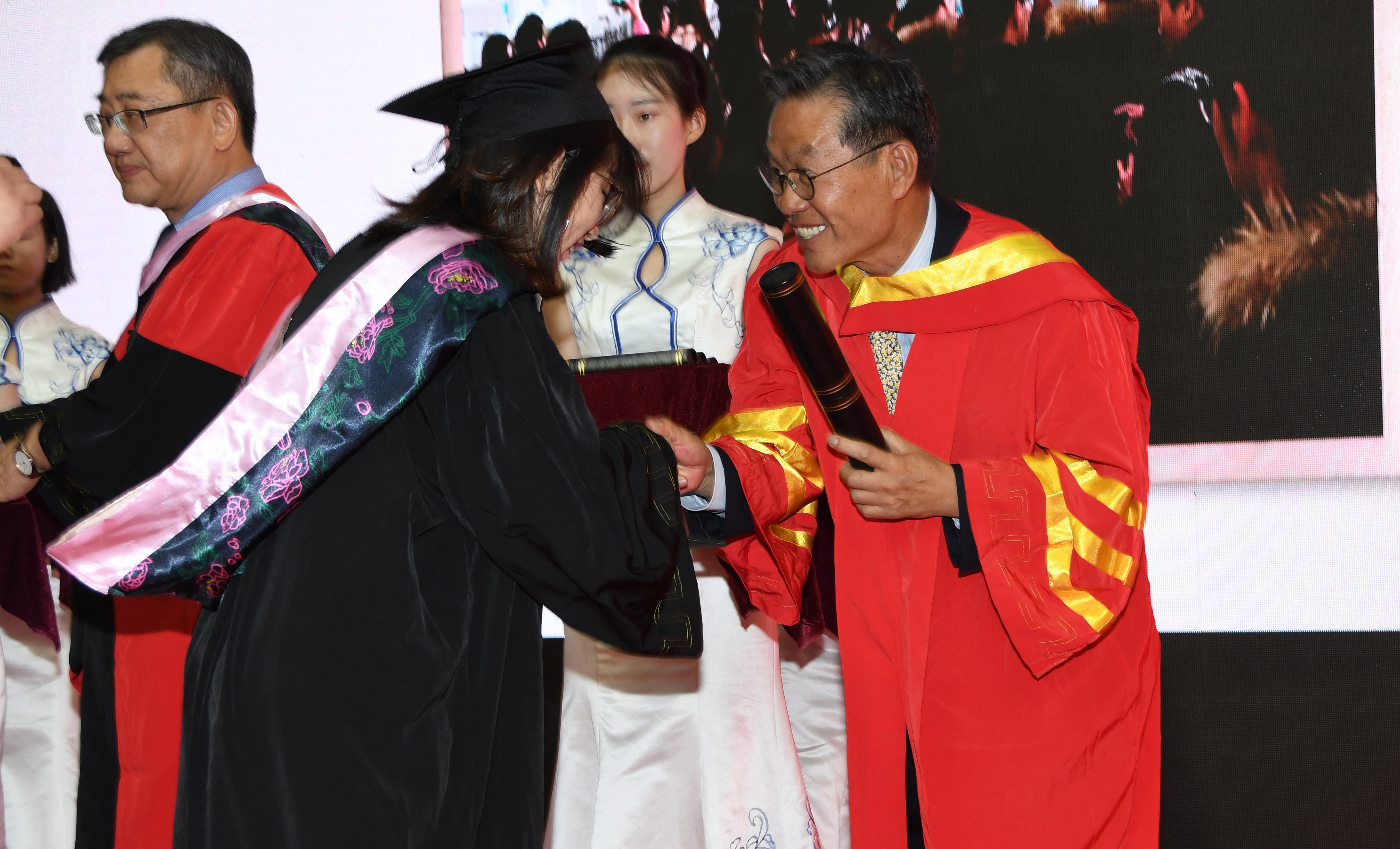 Dr. Youngski Kwak, DSU professor of accounting, presents a diploma to one of the graduates.