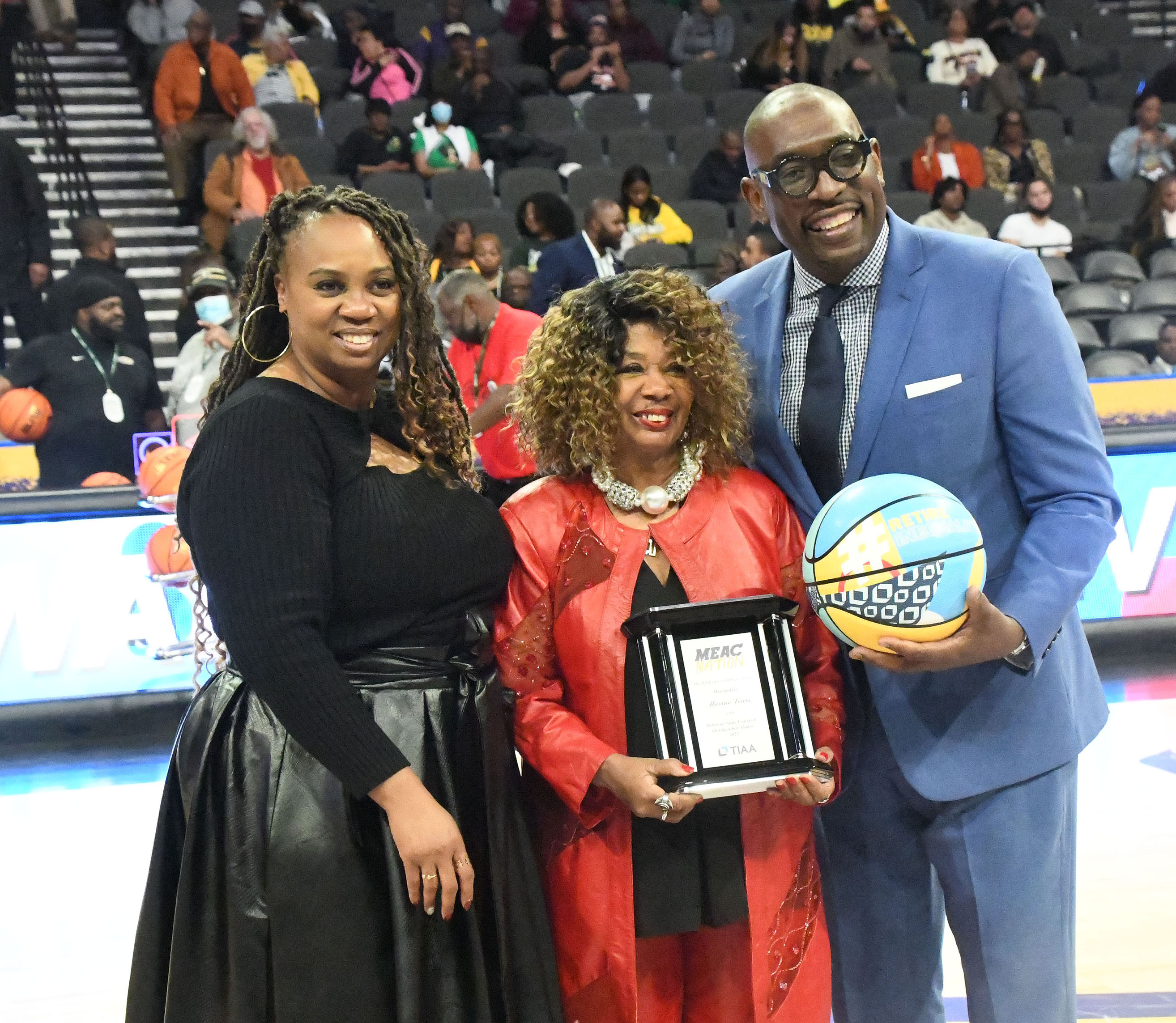 Maxine Lewis holds her Distinguished Alumnae Award standing with the MEAC Commissioner Sonja Sills and an unidentifed presenter.