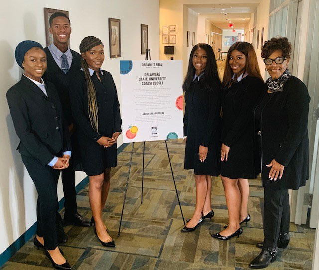 Del State students dress in the donated professional attire pose with Coach Foundaton's Peythia Stubbs.