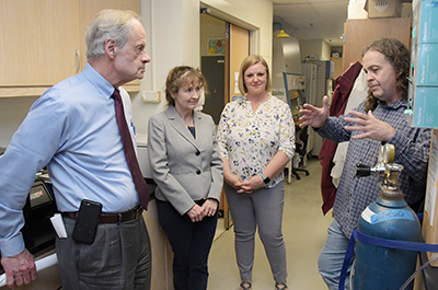 Dr. Michael Gitcho (left) updates US Sen. Tom Carper on Alzheimer research. Drs. Melissa Harrington and Sabrina McGary listen.