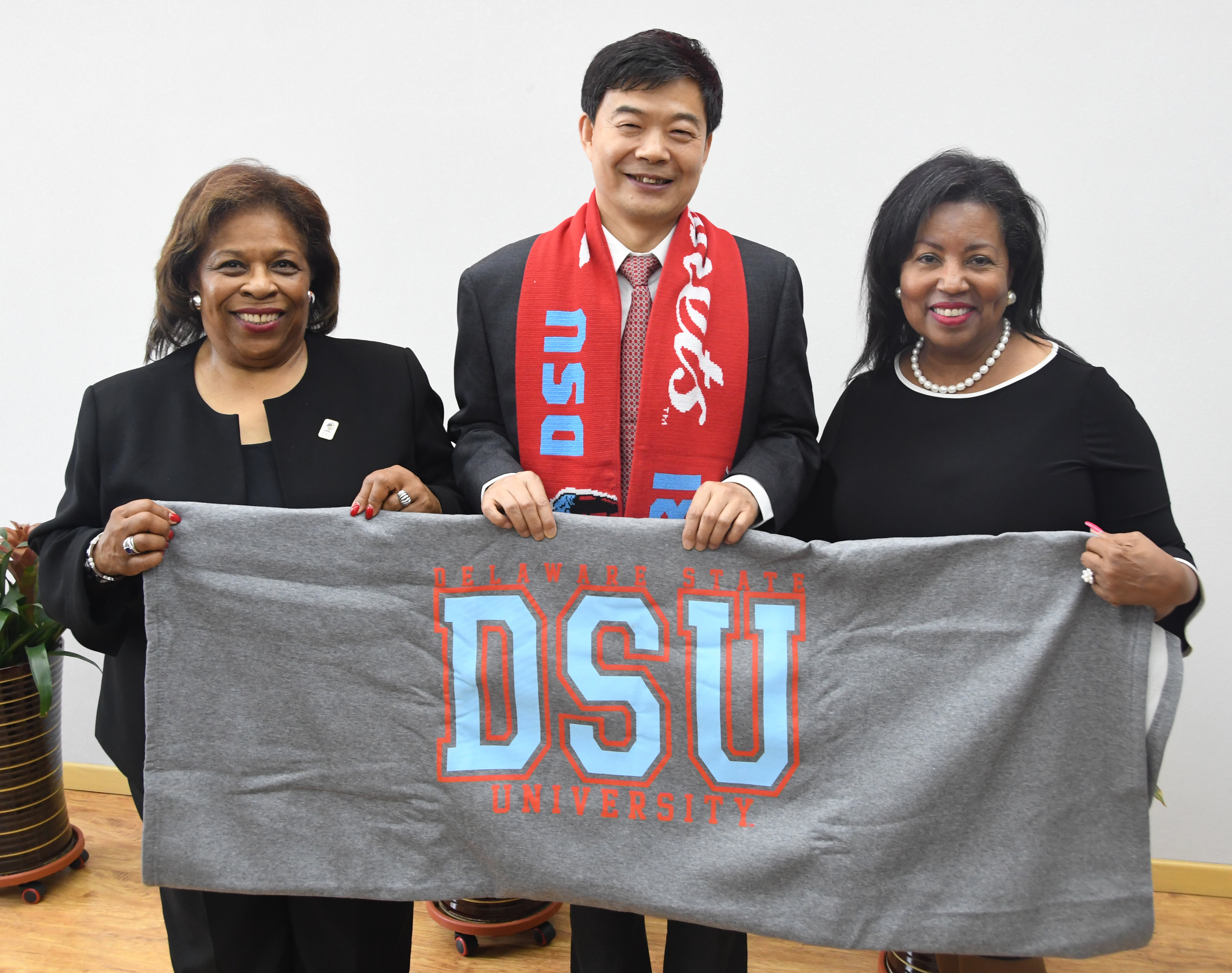 Dr. Wilma Mishoe, left, and Dr. Devona Williams present Su Zhongmin, president of the Changchun University of Science and Technology, with a DSU blanket and scarf.