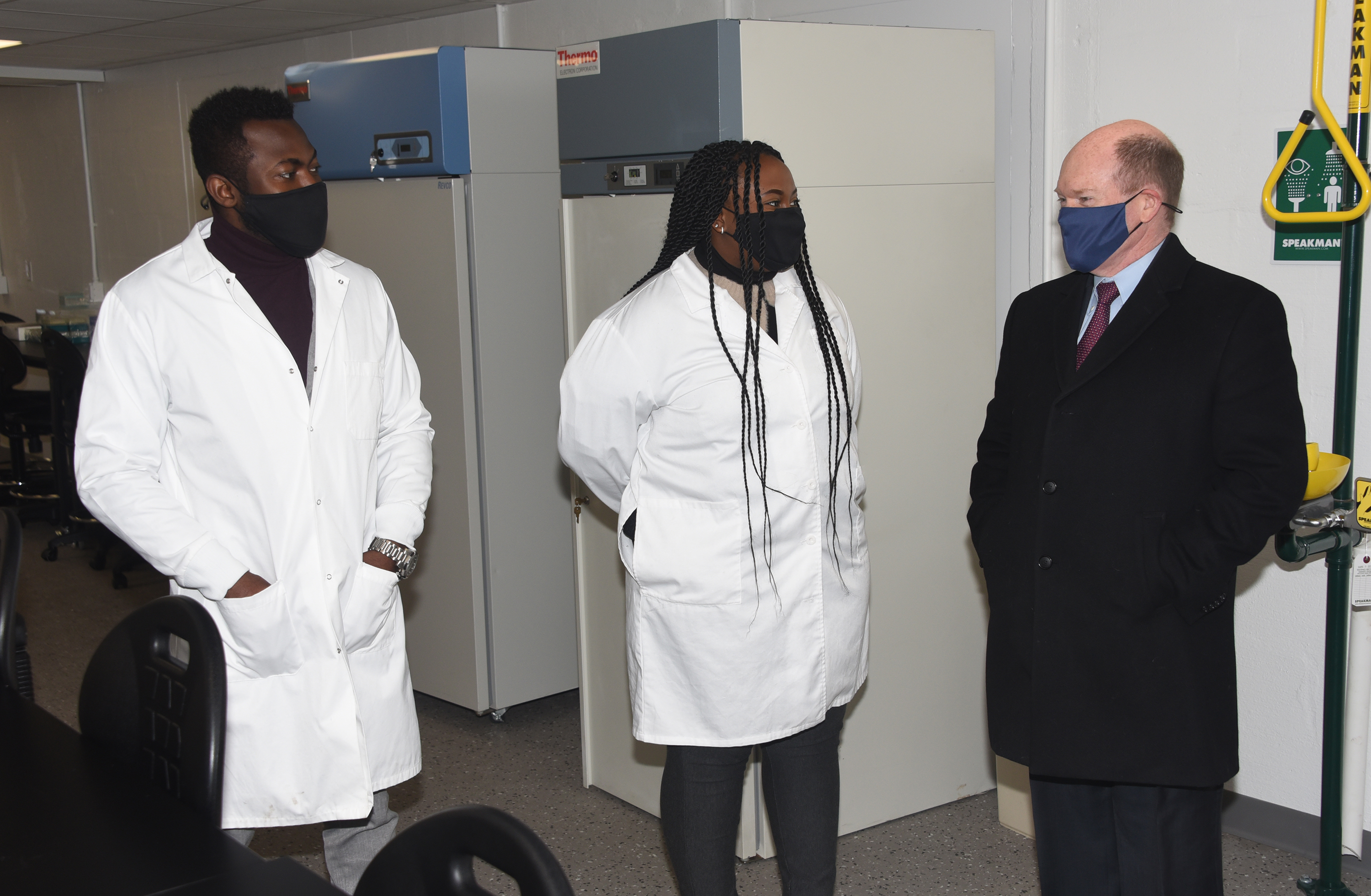 (L-r) Edward Addison and Audrey Janga -- University Alumni who work in the lab -- talk about their work with Sen. Chris Coons.