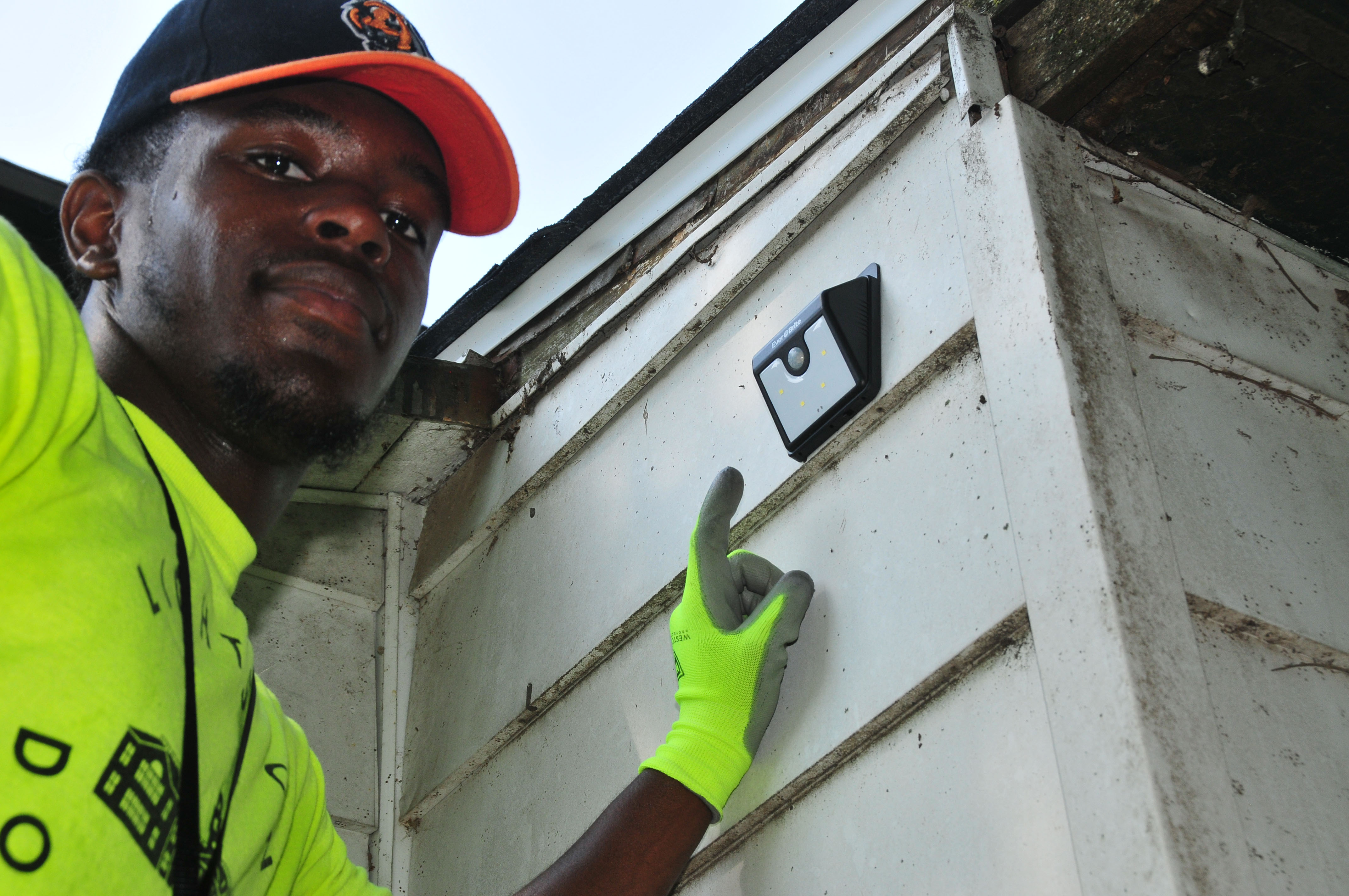 DSU student Eric Wright points to a motion floodlight he just installed at a Dover home.