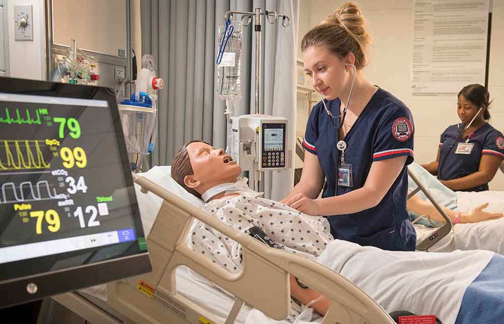 A nursing student gets hands-on experience with a simulator patient, which expresses human reaction and illness symptoms.