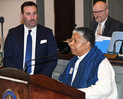 Rev. Rita Paige talks about her mother Hattie Mishoe in the House Chamber. Resolution co-sponsor Sean Lynn (r) listens.