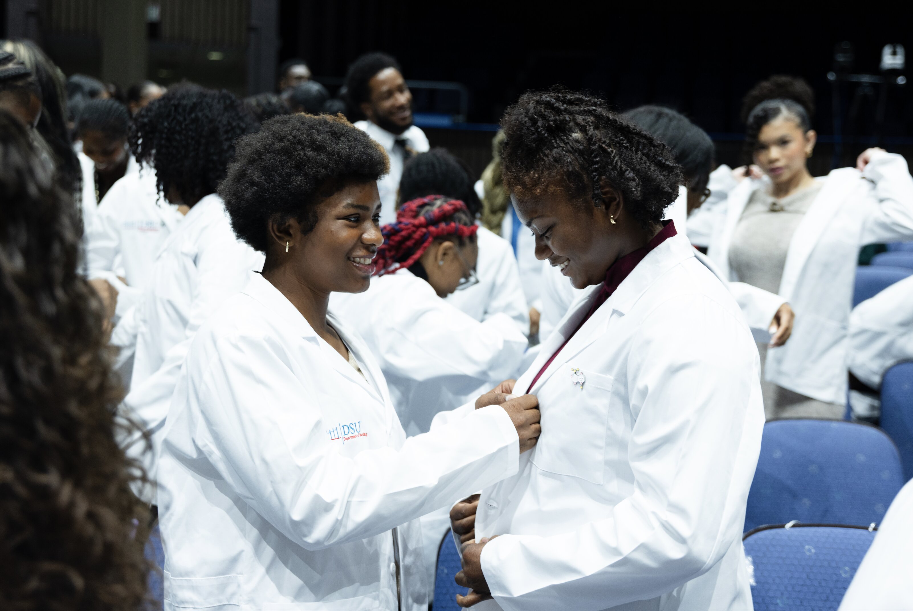 DSU students share a moment as they put on their new white coats.
