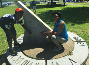 Dr. Kami Fletcher (l) and her 11-year-old son Jayvyn point to their last name on a historic sun dial memorial in Nova Scotia
