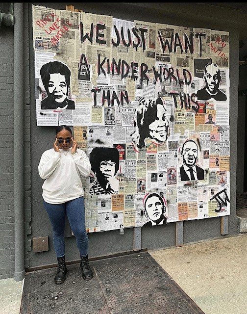 Jannah Williams stands with her mural work at the former Nomad Bar in Wilmington.