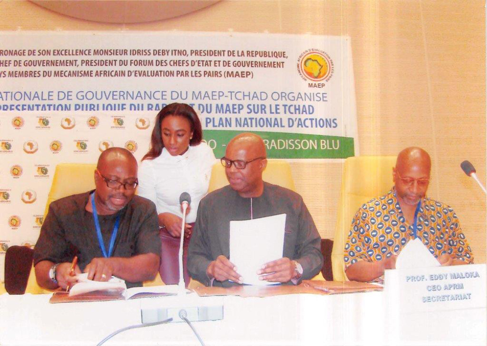 (L-r seated)  DSU's Dr. Akwasi Osei, associate dean of the College of Humanities, Education and Social Sciences, Dr. Eddy Maloka, CEO OF APRM, and Ezrah Aharone, DSU adjunct associate professor of history and political science, sign the partnership document in the African country of Chad, while an identified woman assists them.