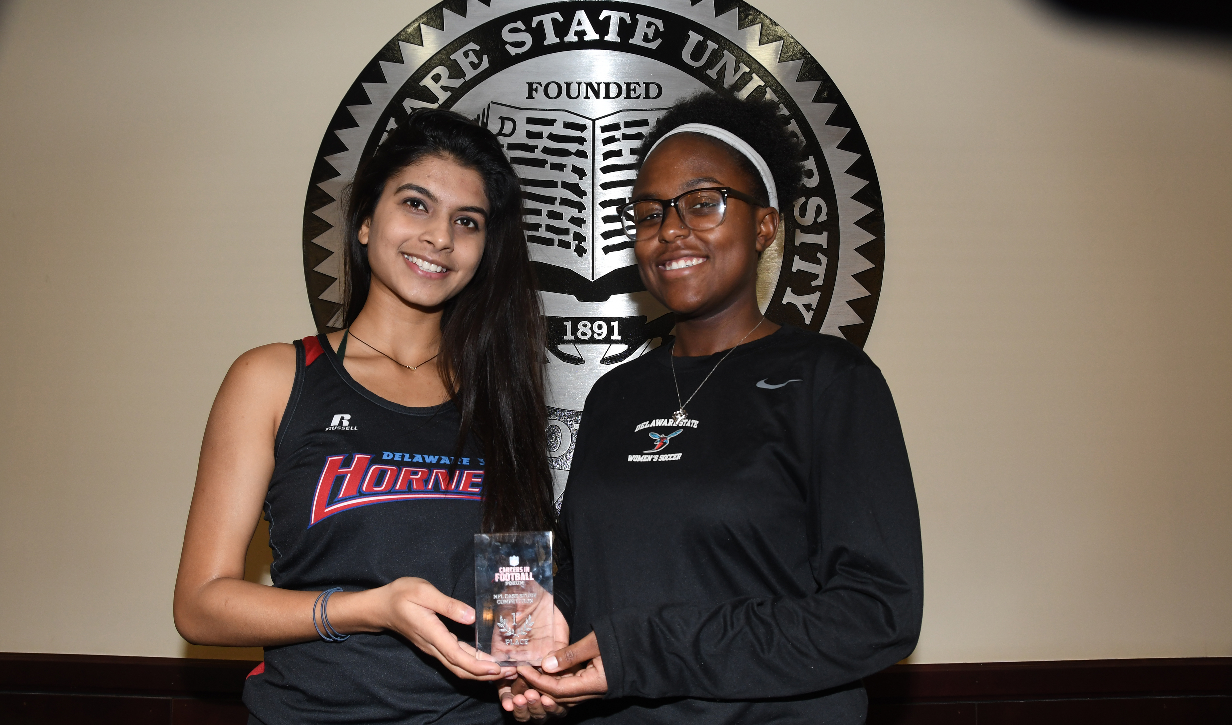 (L-r) Aayushi Chouhan and Braxton Clark represented the University well as they were on the first and second place teams, respectively, in the Business Case Studies Competition at the recent NFL Careers in Football Forum held in Atlanta. The two are holding Ms. Chouhan's first-place trophy (Ms. Clark has already placed her second place trophy in her parent's home).