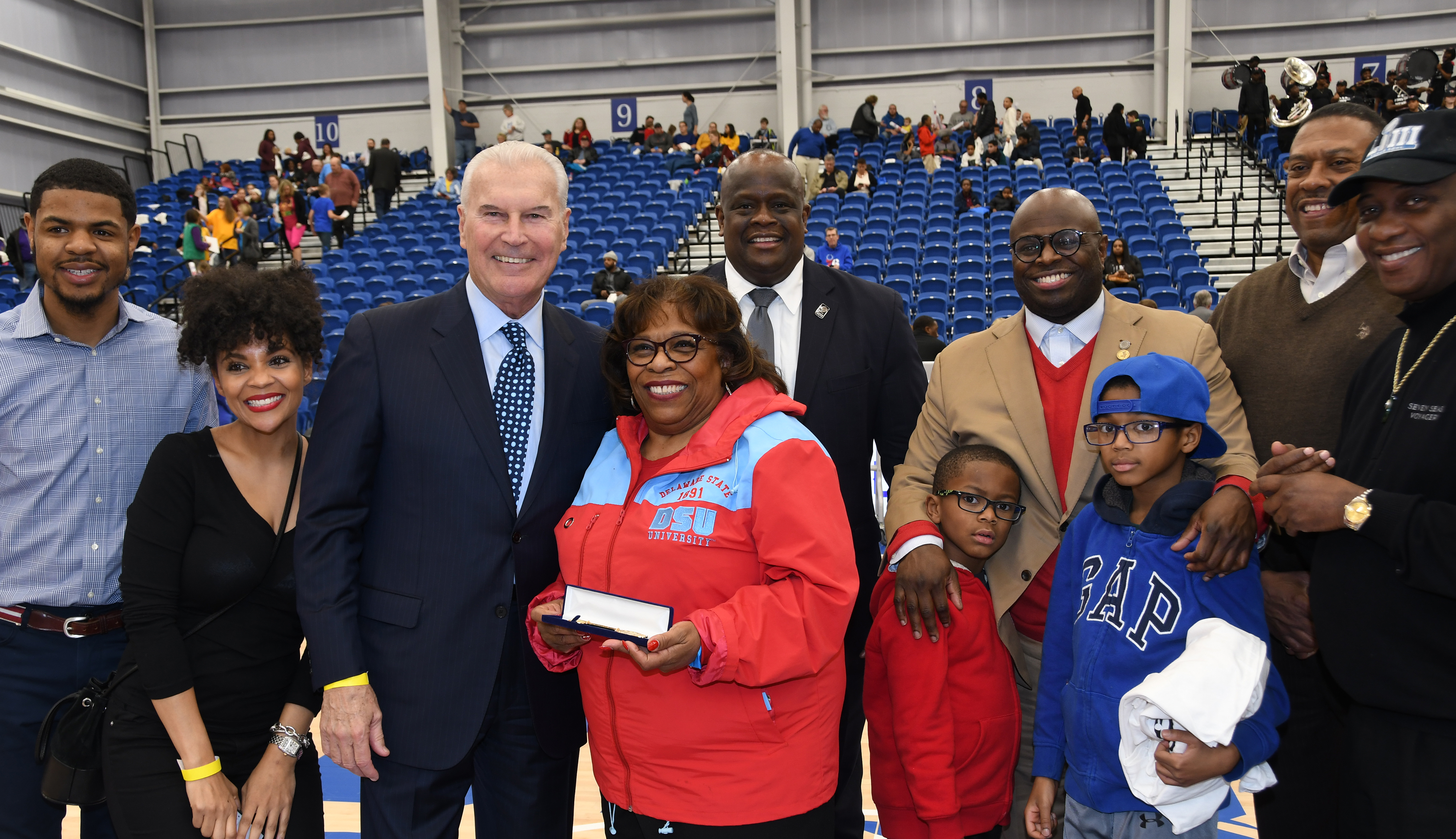 Dr. Wilma Mishoe stands next to Wilmington Mayor Michael Purzycki as she is honored  by the city as part of their annual Black History Month celebration at the 76er Fieldhouse as part of the Long Island Nets vs. Delaware Blue Coats basketball game. Standing around them are city officials and DSU community members.