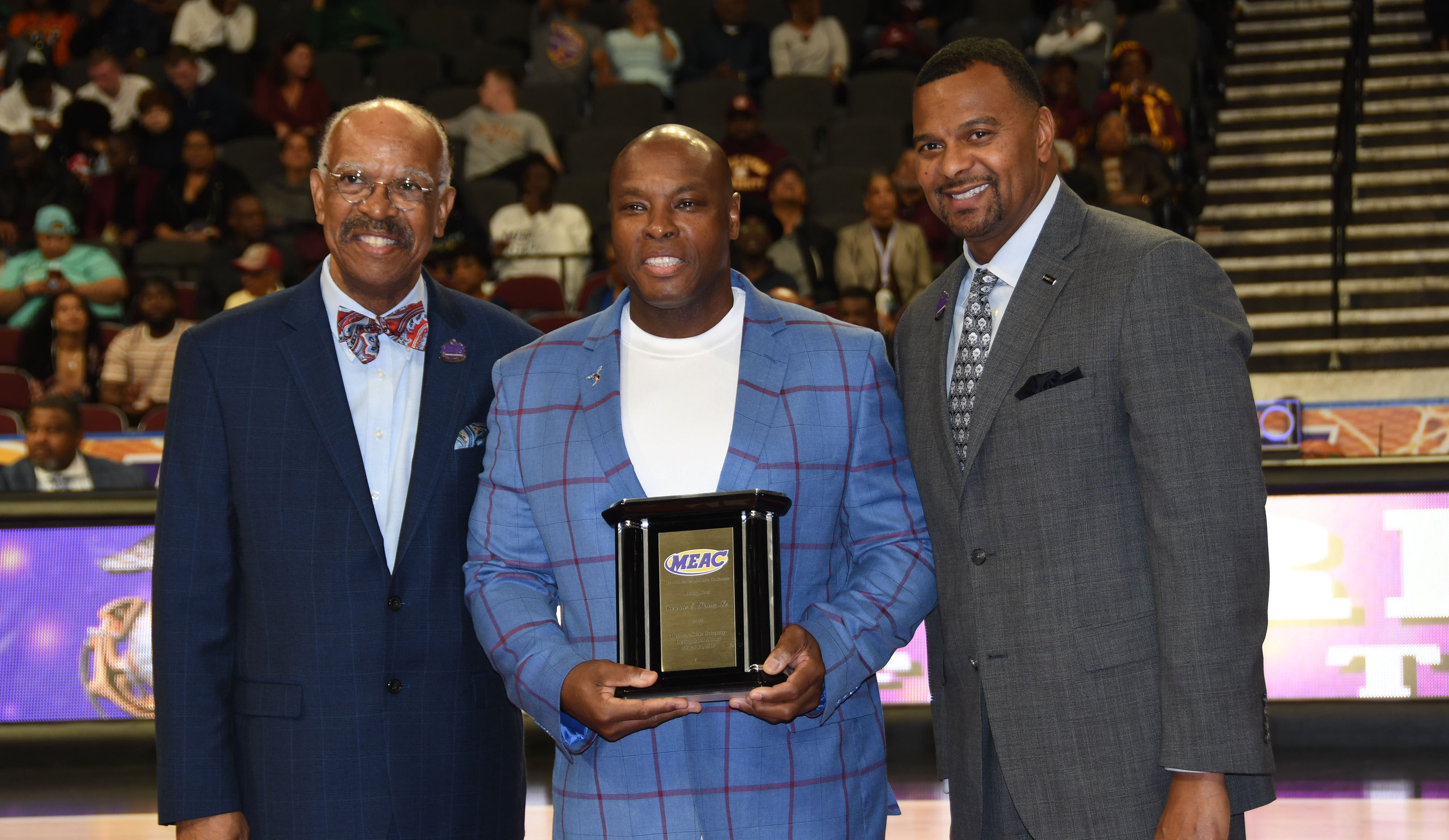 Delaware State University's 2019 Distinguished Alumnus of the Year Ronnie Shaw Sr. (center), receives the award from Dr. Irving H. Smith (l), president of the MEAC Delegate Assembly, and James Church of Priority Automotive, tournament sponsor.