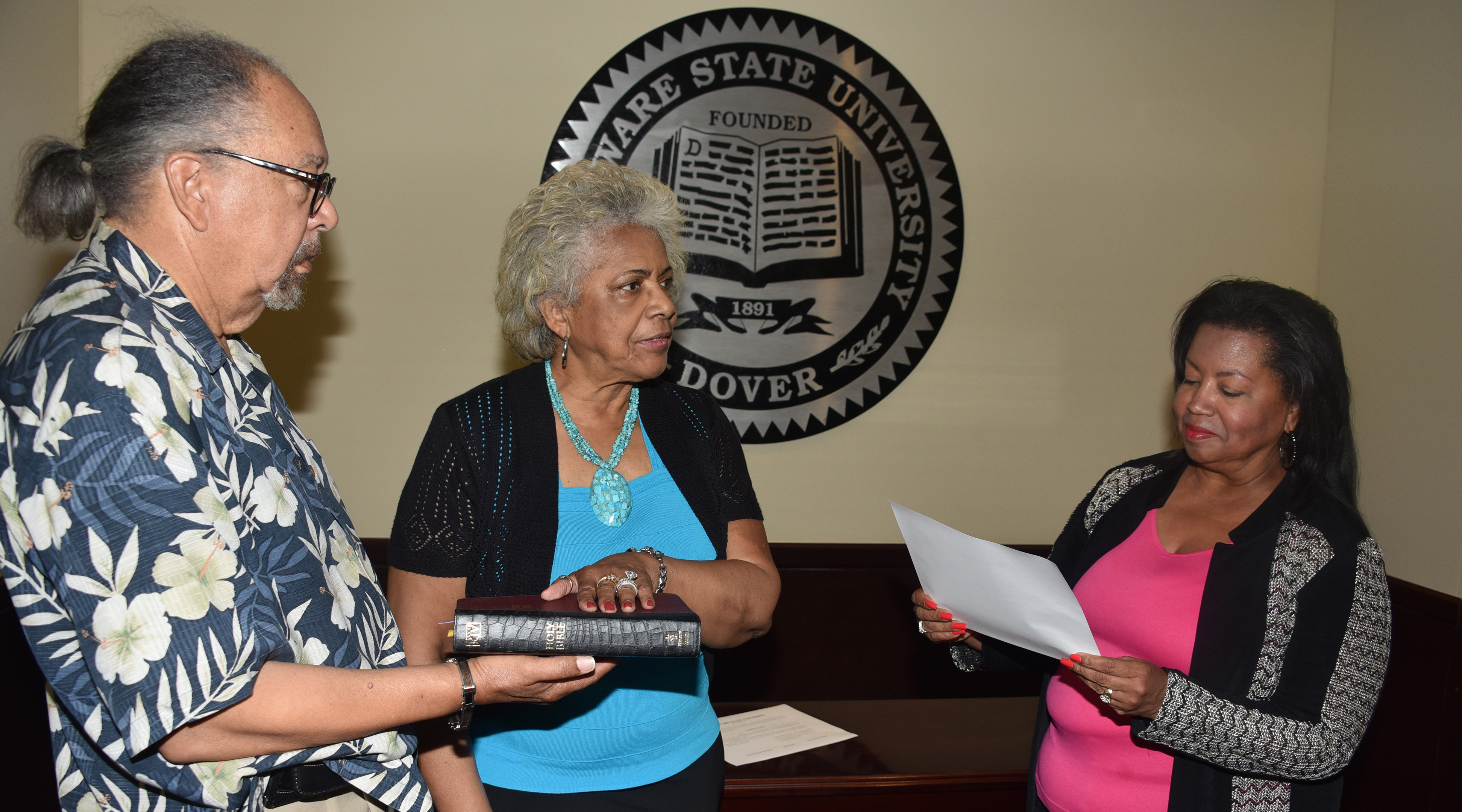 J. Cagney France, fiance of Esthelda Parker Selby, center, holds the bible as she is sworn in as a Board of Trustees member by Board Chairperson Devona Williams.