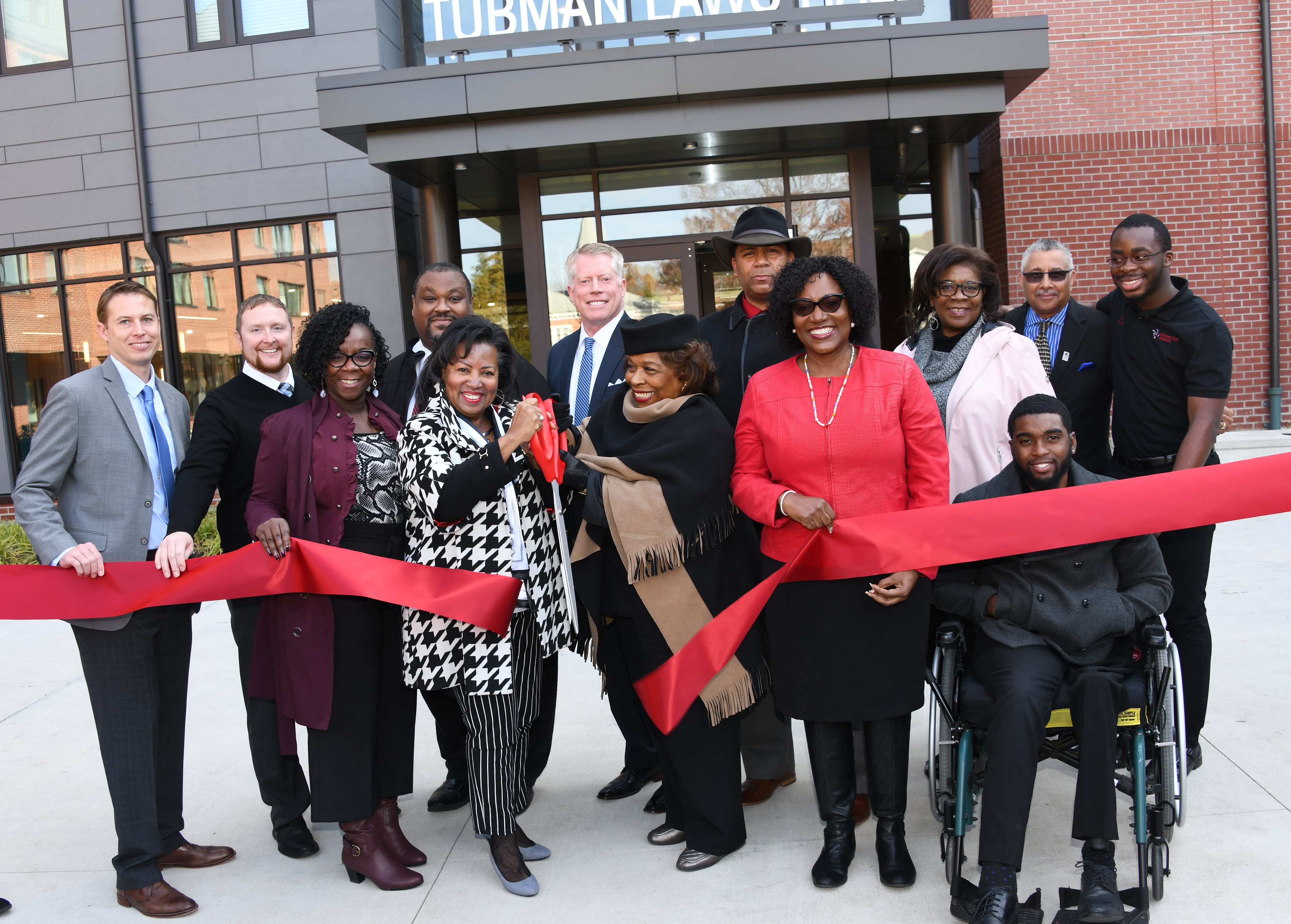 Dr. Devona Williams (with scissors) and University President Wilma Mishoe and others take part in the ribbon-cutting ceremony to formally christen the new Tubman-Laws Residential Hall.