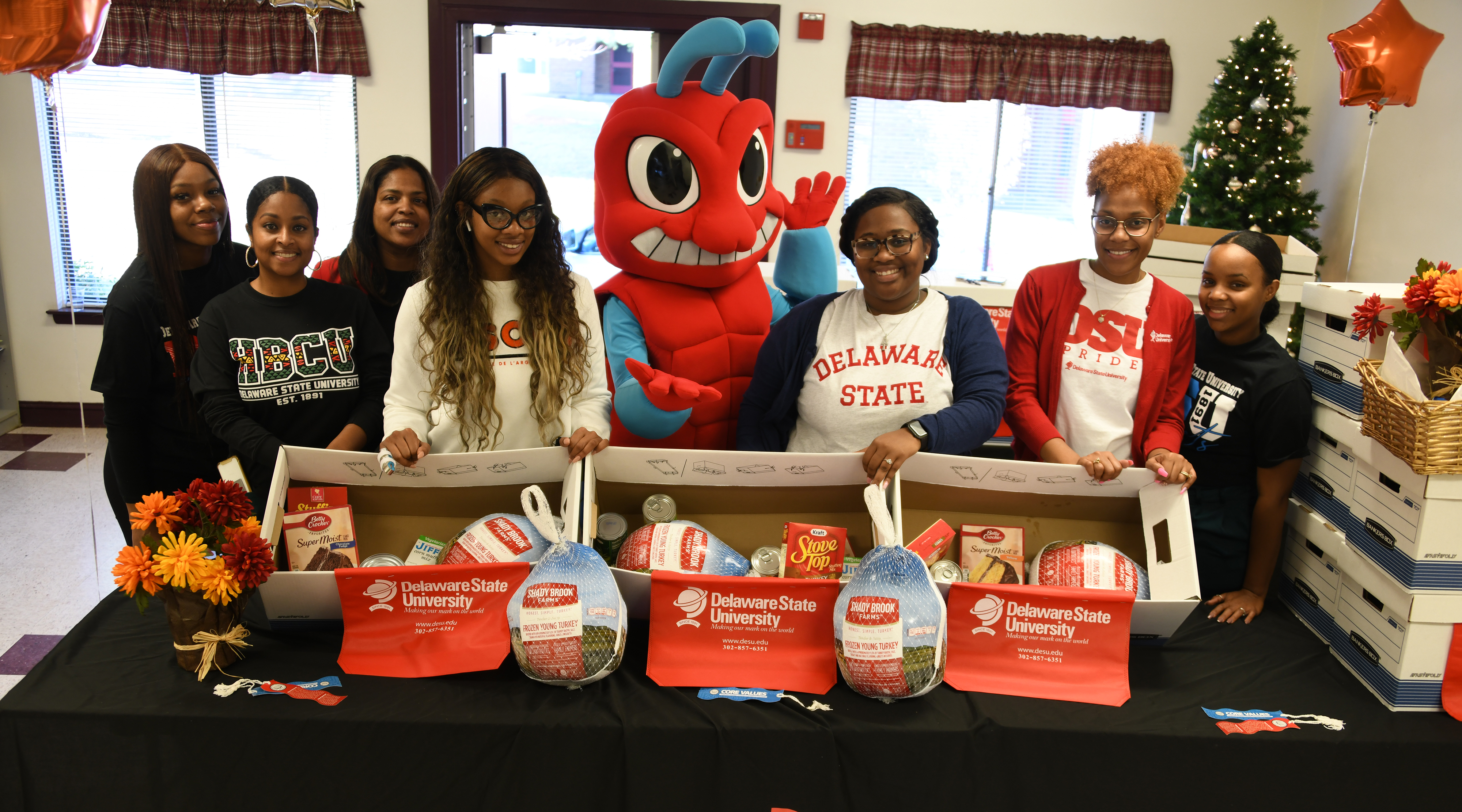 These Enrollment Management members -- (l-r) Destiney Woodson, Shelvia Wright, Andrea Wilson, Siara Bey, the Too Fly Hornet Mascot, Melayna Hall, Tiara Dennis, and Gernelle Forrest -- distributed Thanksgiving dinner items in Smyrna. Another group of their colleagues did the same at a Dover location