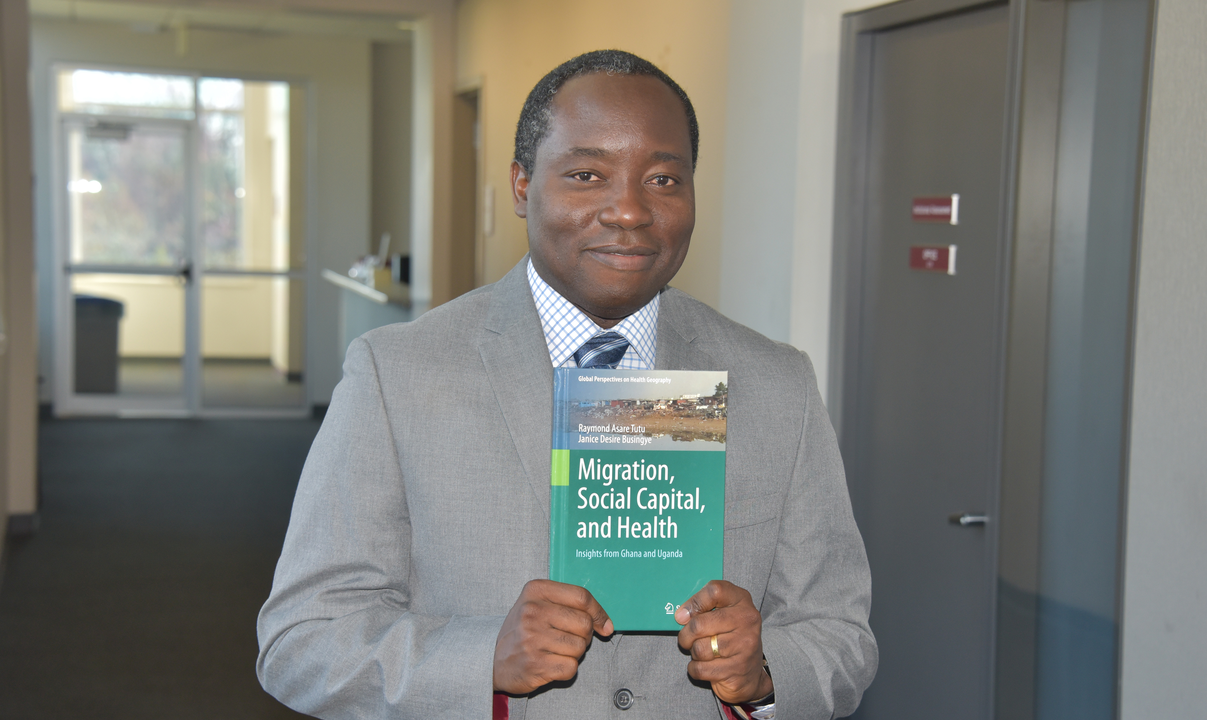 Dr. Raymond Tutu, chair of the Department of Sociology and Criminal Justice, shows a book he has coauthored on Migration, Social Capital and Health in Ghana and Uganda.