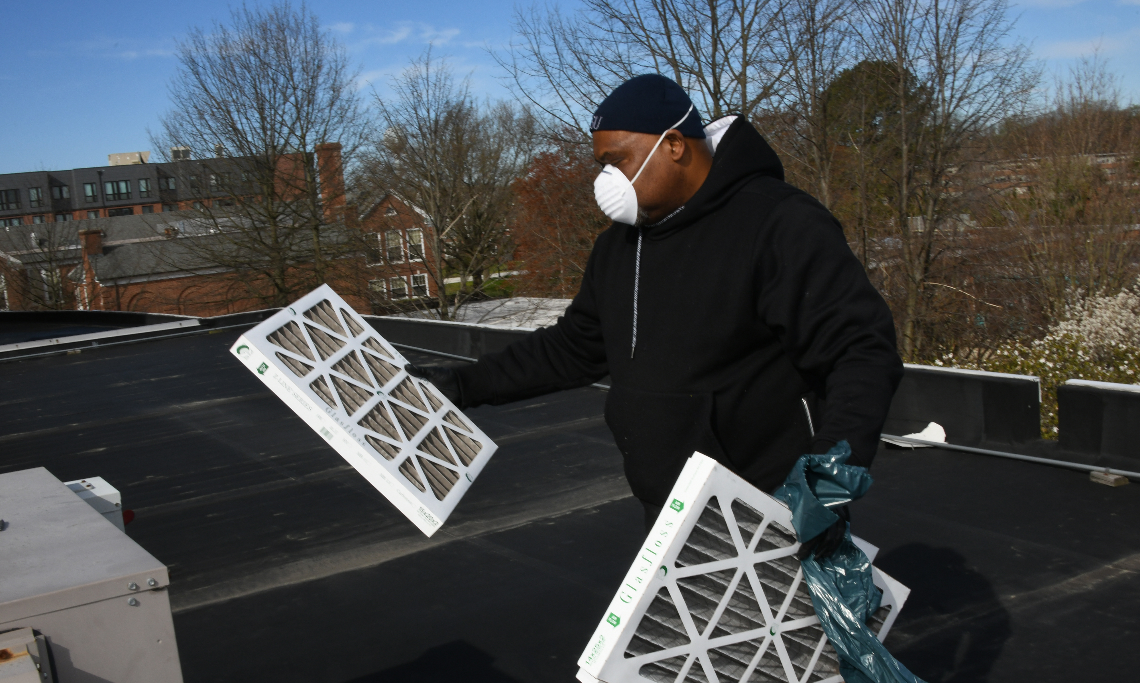 Angelo Albarran Jr. replaces HVAC filters on the roof of the Jason Library, but with allergies and asthma combined with the ongoing COVID-19 pandemic he leaves nothing to chance, working while wearing a facemask.