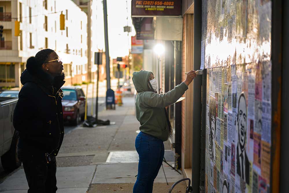 Jannah Williams, who graduated in 2018 with a BA in Studio Art from Del State, is shown in this 2020 photo creating a mural with a bystander watching in downtown Wilmington in the wake of the riots that resulted from the police-related death of George Floyd, After being on display in a Wilmington storefront, the Delaware Division of the Historical and Cultural Affairs acquired it to be a part of its collections. The work is currently on exhibition at the Longview Museum of Fine Arts in Texas. Photos by Joe del Tufo.