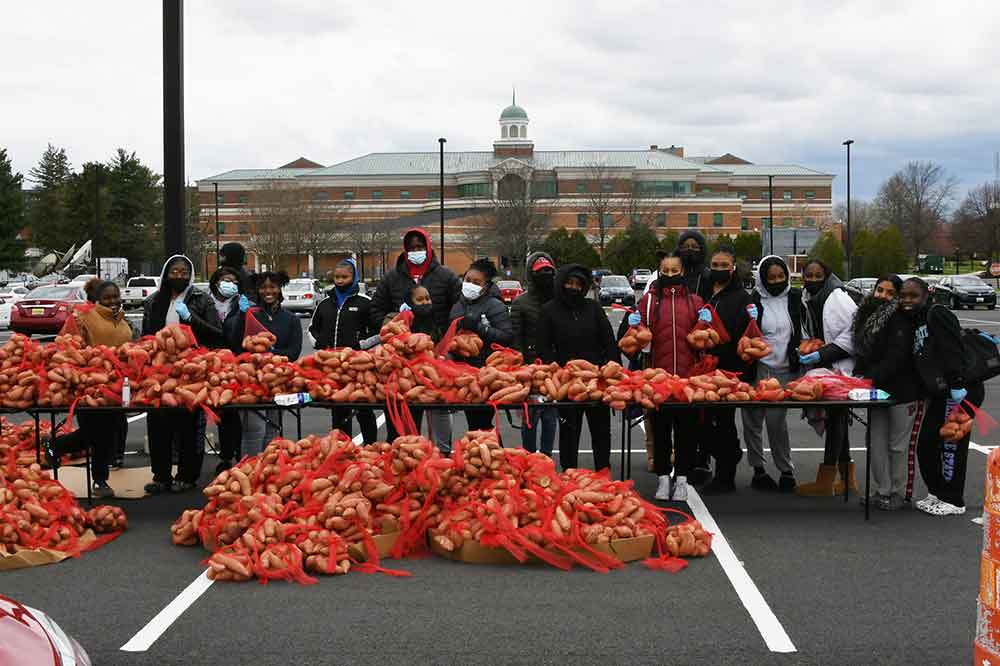 Some of the 190 students that volunteered pose with a portion of the 20,000 pounds of sweet potatoes that they gave away to motorist as part of an April 10 community service project.