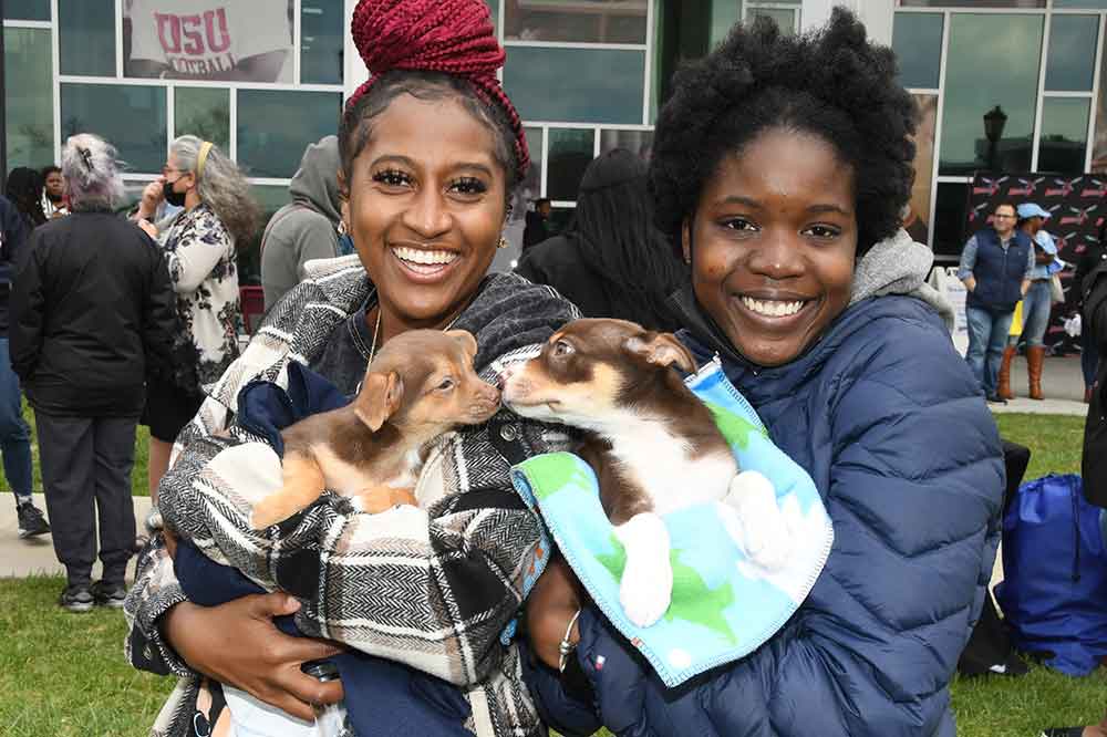 Two students take advantage of the "Doggy De-stress Station" that was a part of the April 27 Unity Day activities at Delaware State University. 