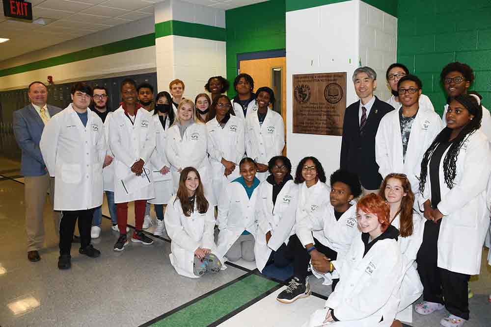 Dr. Chad Harrison, St. Georges Technical HS principal (far left), and the University's Dr. Jung-Lim Lee (black suit jacket) poses with St. Georges science students outside of the new Satellite Lab at the high school 