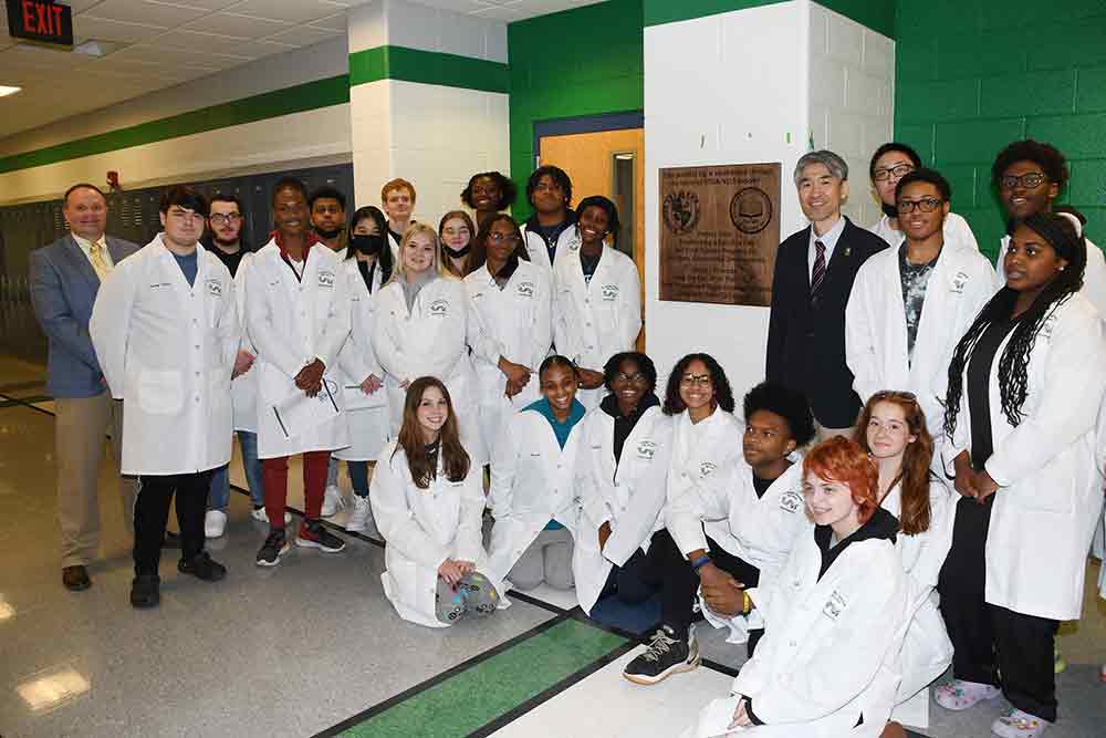 Dr. Chad Harrison, St. Georges Technical HS principal (far left), and the University's Dr. Jung-Lim Lee (black suit jacket) poses with St. Georges science students outside of the new Satellite Lab at the high school