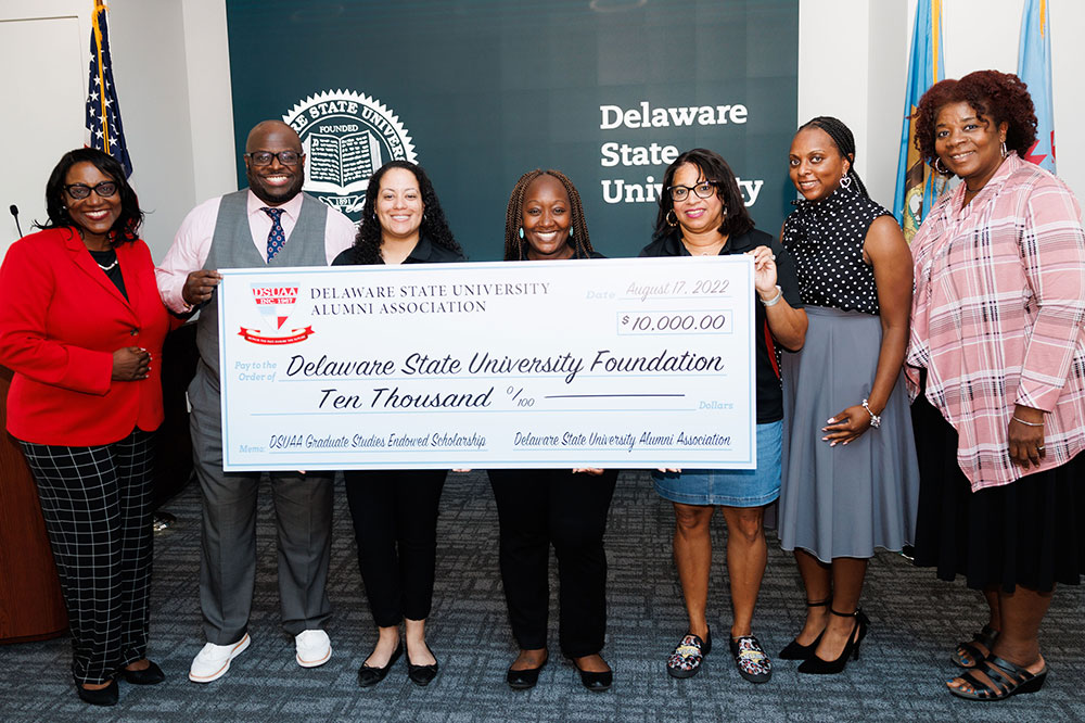 (L-r) Dr. Vita Pickrum, VP of Institutional Advancement, University President Tony Allen; DSUAA officers Leah Williams, Diane Kirby and Antionette Blake; and Office of Alumni Affairs officials Tanisha Baker and Dr. Marcia Taylor, stand with a display check representing the new DSUAA endowed scholarship that will help alumni continue their studies.