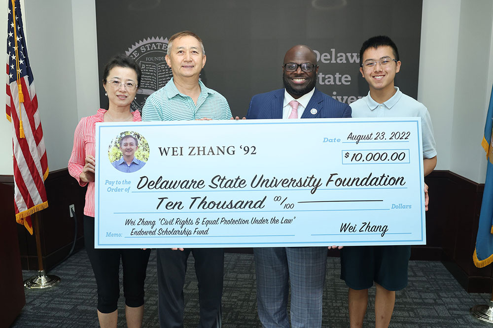 Wenyi and Wei Zhang, University President Tony Allen and Gerry Zhang hold a display check symbolizing the establishment by the Zhangs of the Civil Rights & Equal Protection Under the Law Endowed Scholarship Fund. Mr. Zhang is a 1992 graduate of then-Delaware State College.