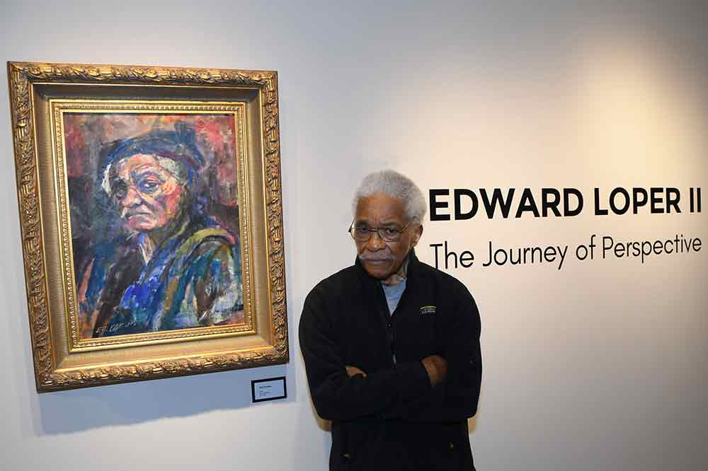 Edward Loper II stands next to one of his self-portrait oil paintings, one of 30 of his works on exhibition at the Arts Center/Gallery at Delaware State University.