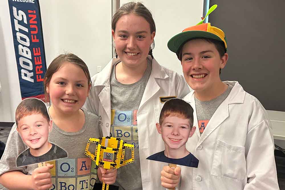 The LOAD Robotics Team members -- (l-r) Josephine Morton, David Morton, and Annette Morton -- hold the 1st place FIRST Lego League Delaware State Championship trophy, as well as pictures of two team members who could not attend the competition.