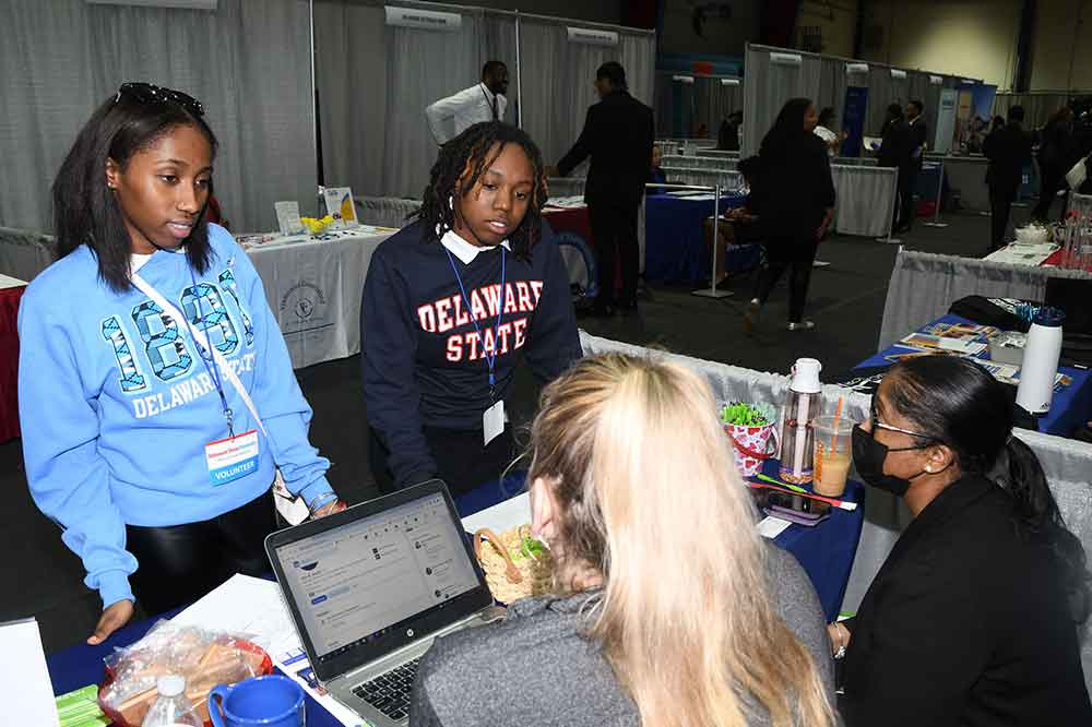 Two University students talk with one of the many corporate and government entities that took part in the 2023 Spring Career Pathways Expo held in the Memorial Hall Gymnasium on March 23.