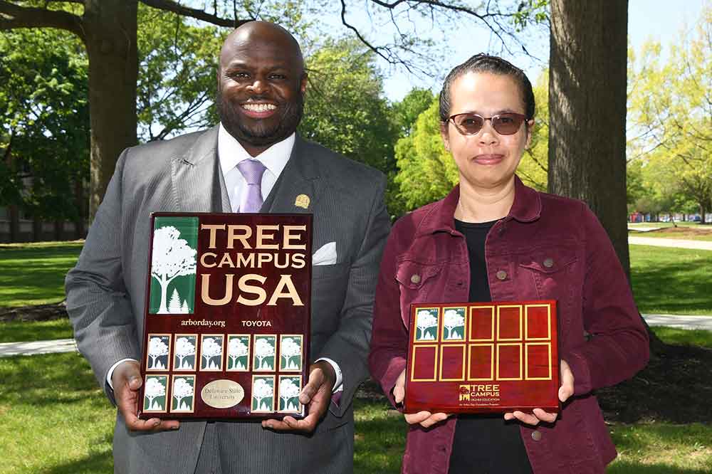 University President Tony Allen and Cynthia Hong-Wa, Curator of the University's Claude E. Phillips Herbarium, hold the institution's Tree Campus USA plaque. The consecutive run of that University distinction made it necessary to extended the annual recognition onto a second plaque.