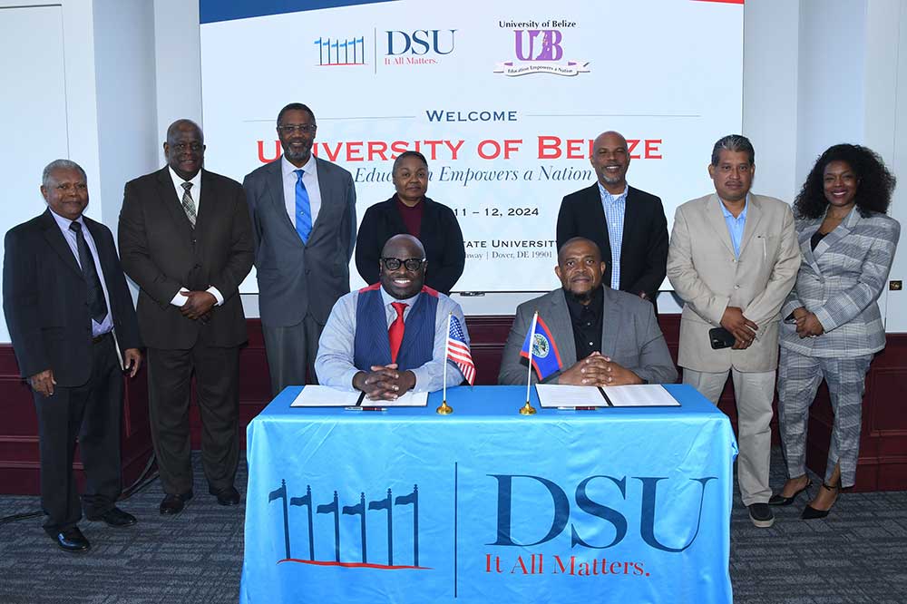 DSU President Tony Allen and University of Belize President Vincent R. Palacio (both seated) prepared to sign a collaborative agreement between the two institutions. Standing behind them are (l-r) DSU's Dr. Marikis Alvarez, Tony Boyle, Belize Ambassador to the U.S. His Excellency Lynn Raymond Young, DSU Provost Saundra DeLauder, UB's Elbert H. Irving, Maximiliano Ortega Jr., and DSU's Dean Cherese Winstead Casson.