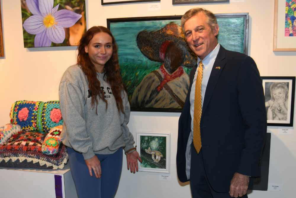 DSU student and arts studio major Chloe Hannah poses with Delaware Gov. John Carney after she showed him her oil painting (by her right hand), which is part of the Delaware State Employees Art Exhibition on display in the DSU Arts Center/Gallery. 