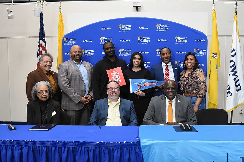 Standing (l-r), Frank DiMarco, Gloucester County Commissioner Director; Jim Jefferson, Gloucester County Commissioner Deputy Director; Rich Cooper, RCSJ Assistant AD and Women's Basketball Coach; Jinelyis Alvarez, RCSJ student; Kareem McLemore, DSU Exec. Director for Admissions; Gisenia Colon. Seated, Almarie Jones, VP and Chief Diversity Officer, Diversity and Equity/Title IX and Compliance, RCSJ; Brenden Rickards, Ph.D., RCSJ Provost and VP of Academic Services; and Antonio Boyle, DSU Senior Vice President of Strategic Enrollment.