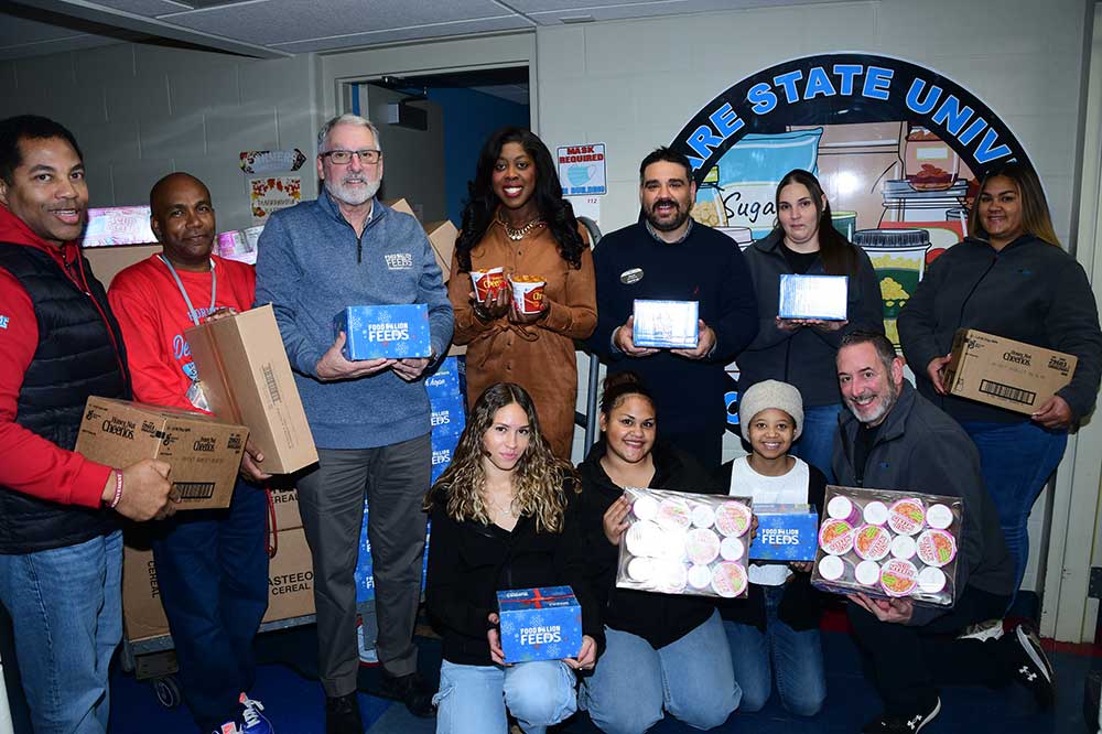Representatives of the Food Lion grocery stores in Dover are joined by DSU student and staff members to pose with some of the 80 cases of non-perishable foodstuff items donated for the DSU Food Pantry facilities on the University's' main campus and the DSU Downtown location. Also pictured, is Joann Means of TD Bank (center standing), who connected Food Lion with DSU.