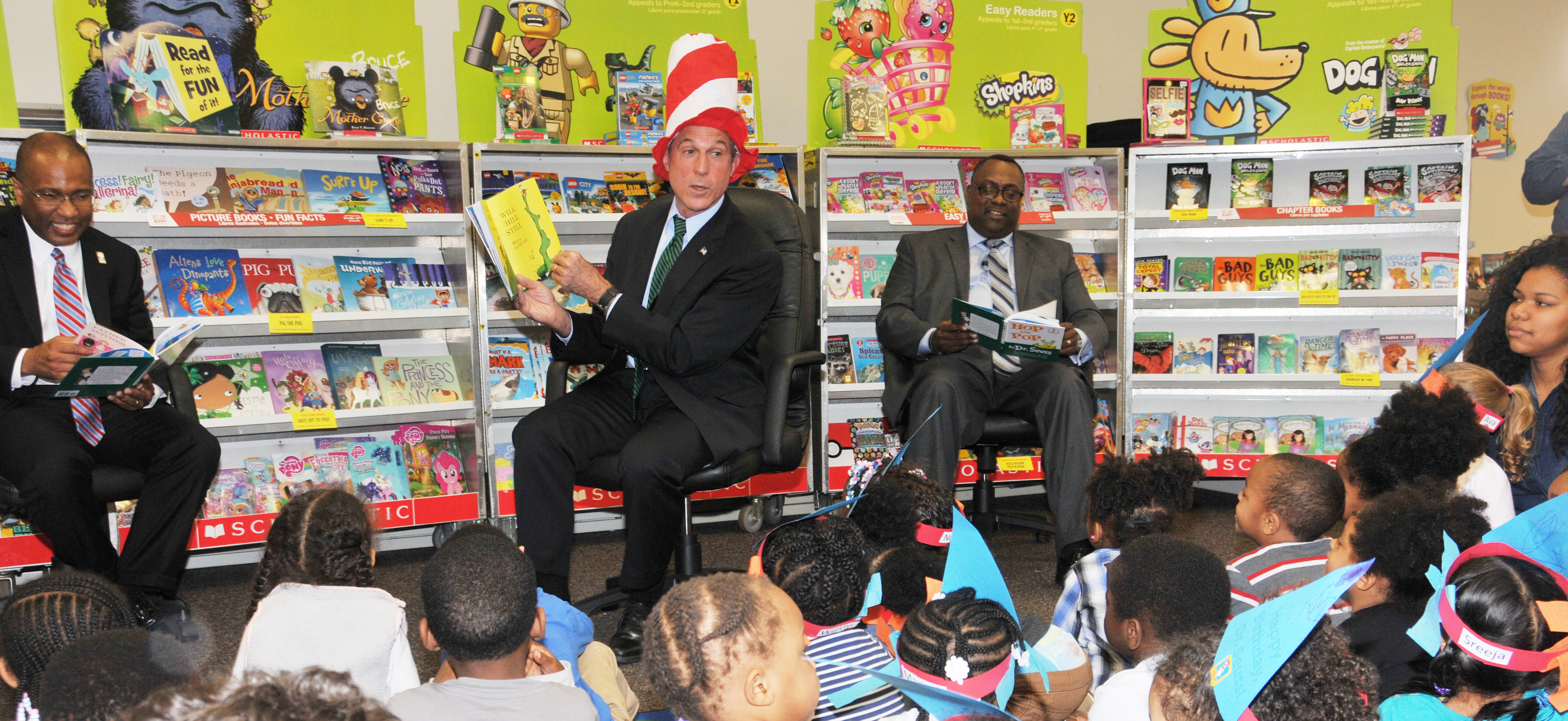 Gov. John Carney reads to the children, while Tyrone James of the United Way of Del. also reads along.