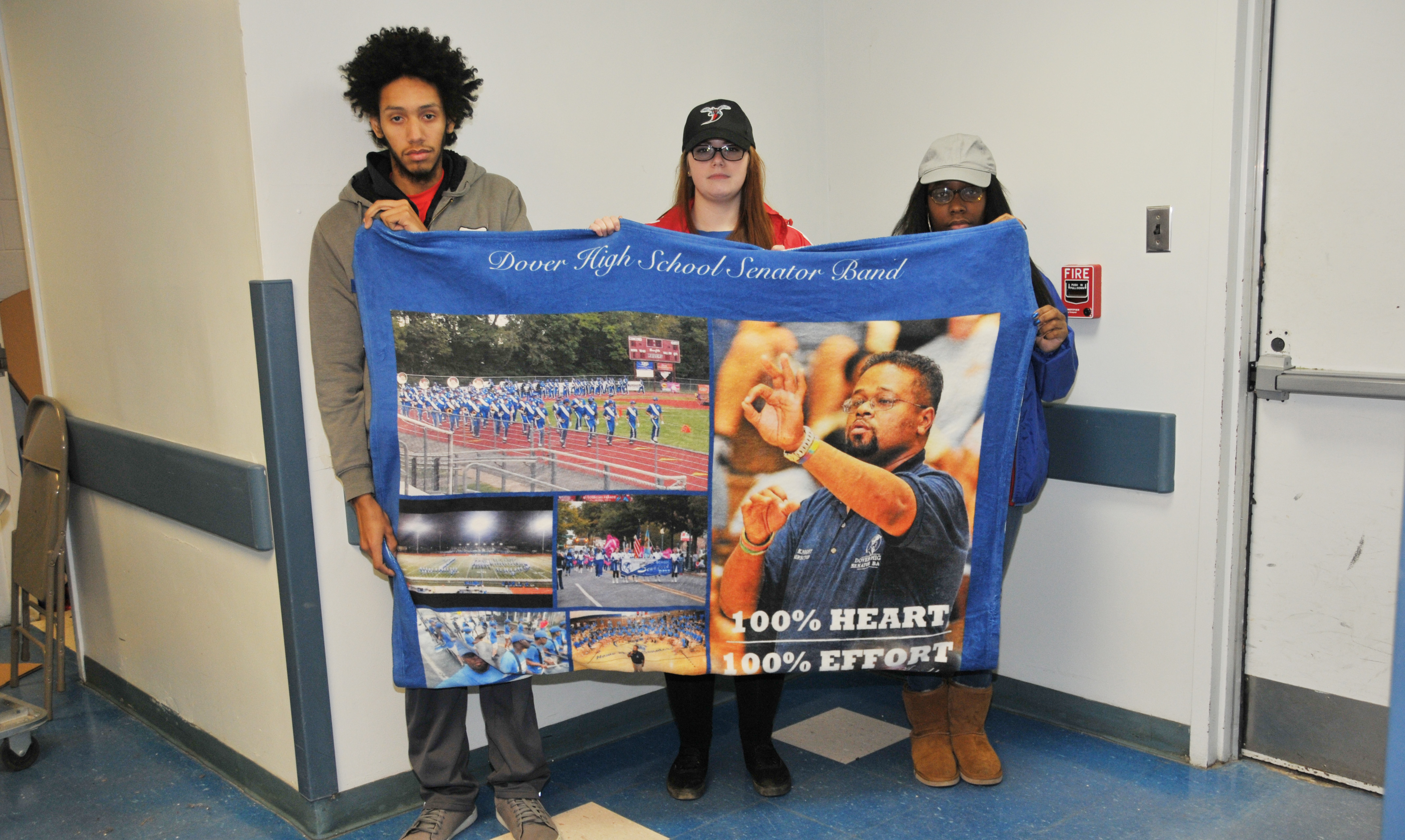 (L-r) Carlos Ortiz, Christina Trice and Akeya Rainer, former Dover HS Band members who were under Lenny Knight's director and then followed him to DSU, hold up a blanket of images that Dover HS presented to Mr. Knight at the end of his tenure there.