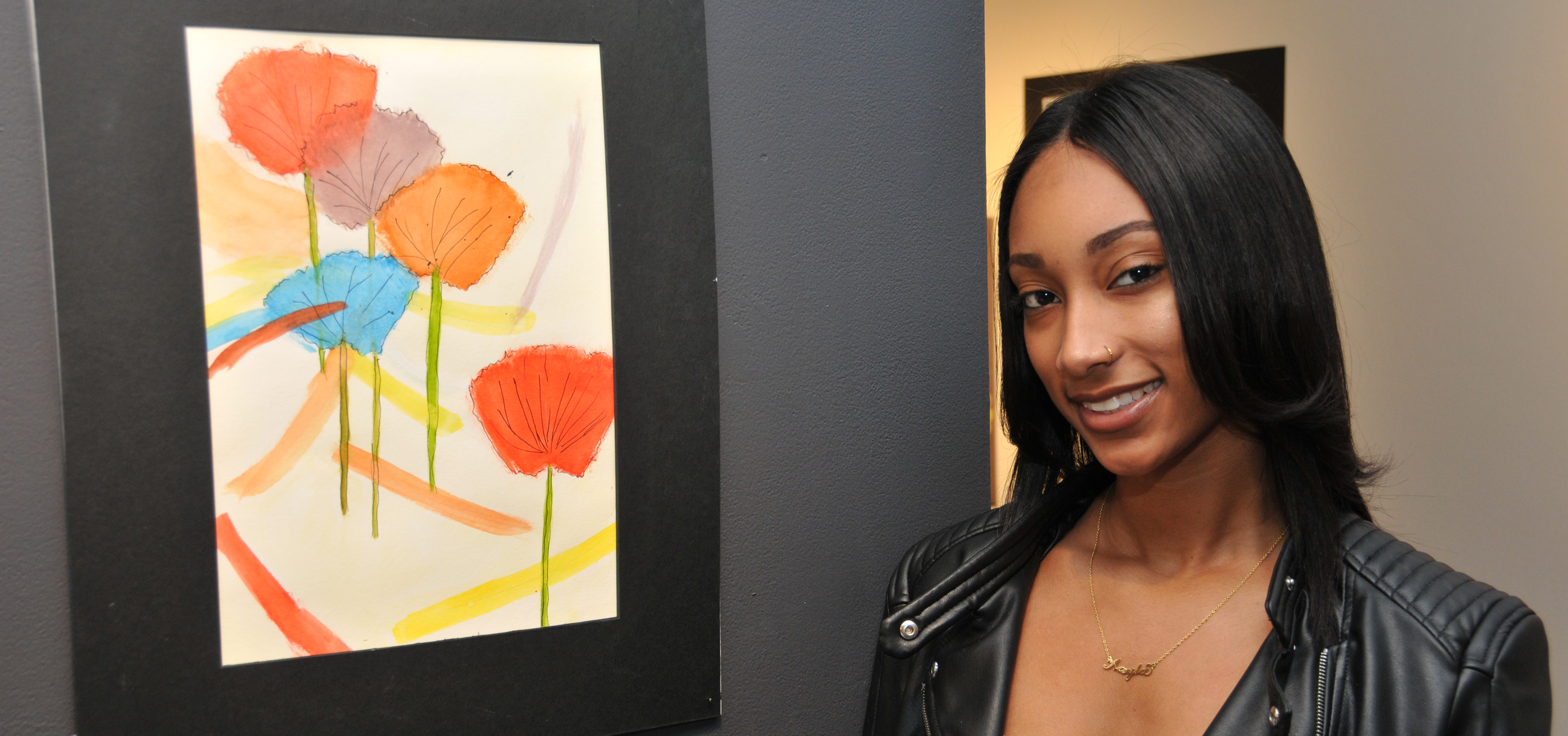 Kayla Redman stands beside her painting entitled "Flowers," which is one of three of her works on exhibition in the Art Student Honors Exhibition