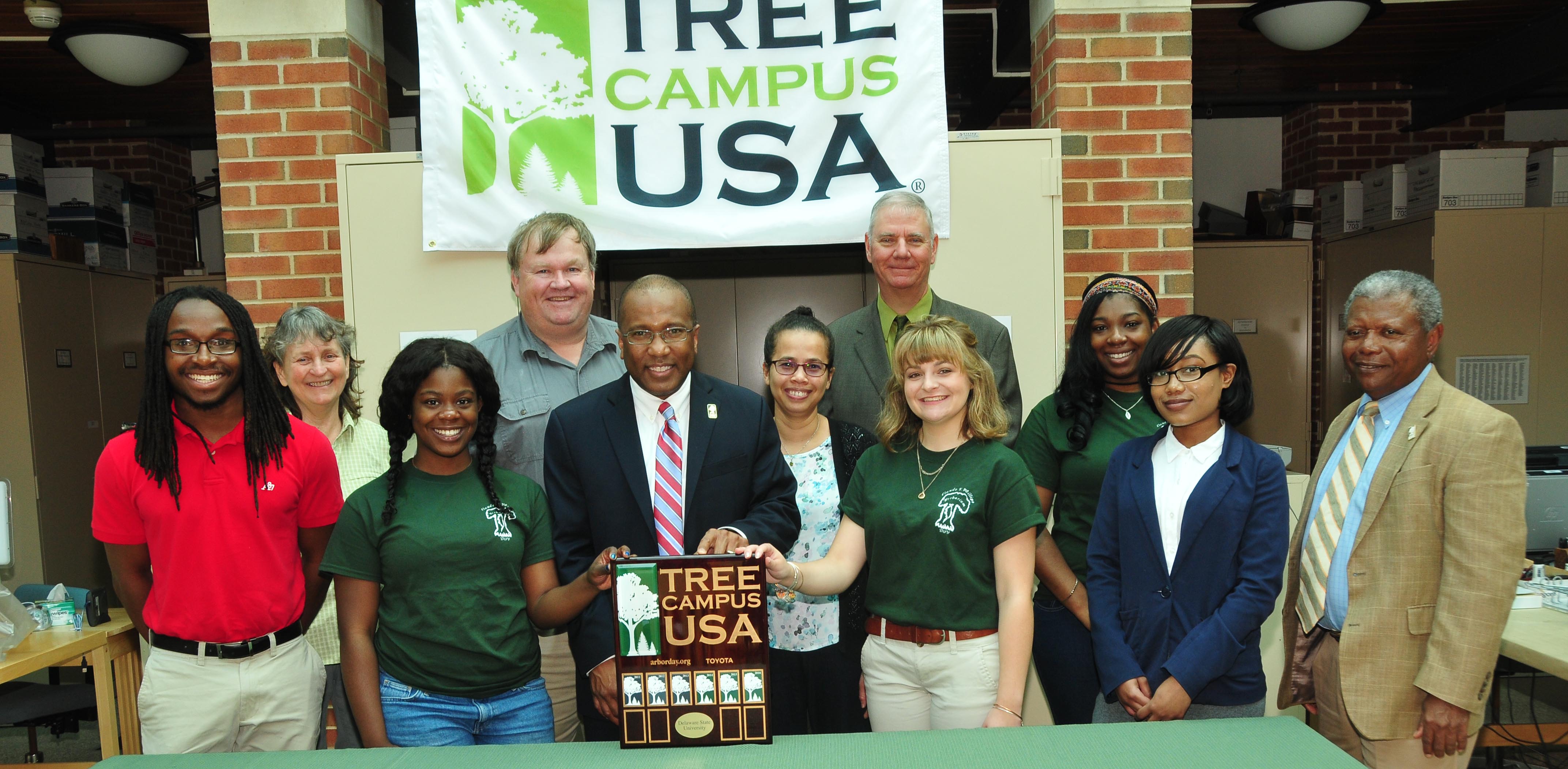 Displaying DSU's Tree Campus USA designation, DSU President Harry L. Williams (center) is joined by DSU faculty members; Dr. Michael Valenti, state forestry administrator, and DSU students.