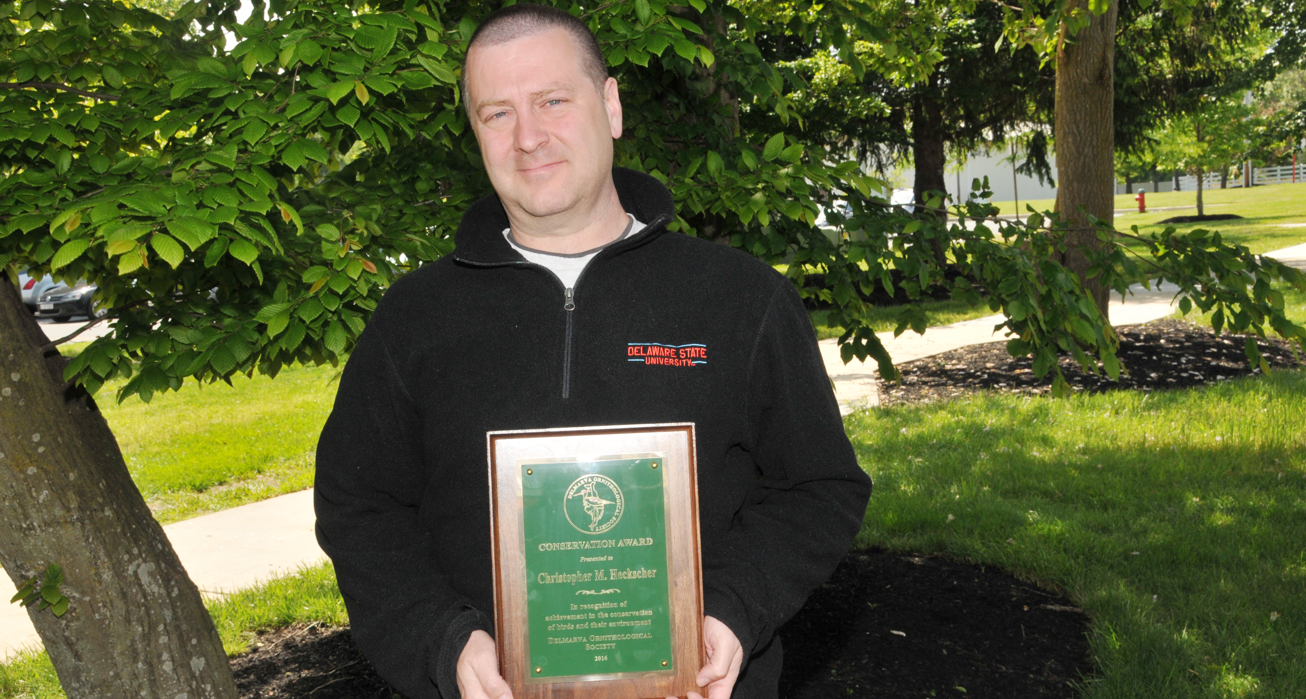 Dr. Christopher Heckscher, associate professor of environmental sciences, holds the Conservation Award he recently receives from the Delmarva Ornithological Society.