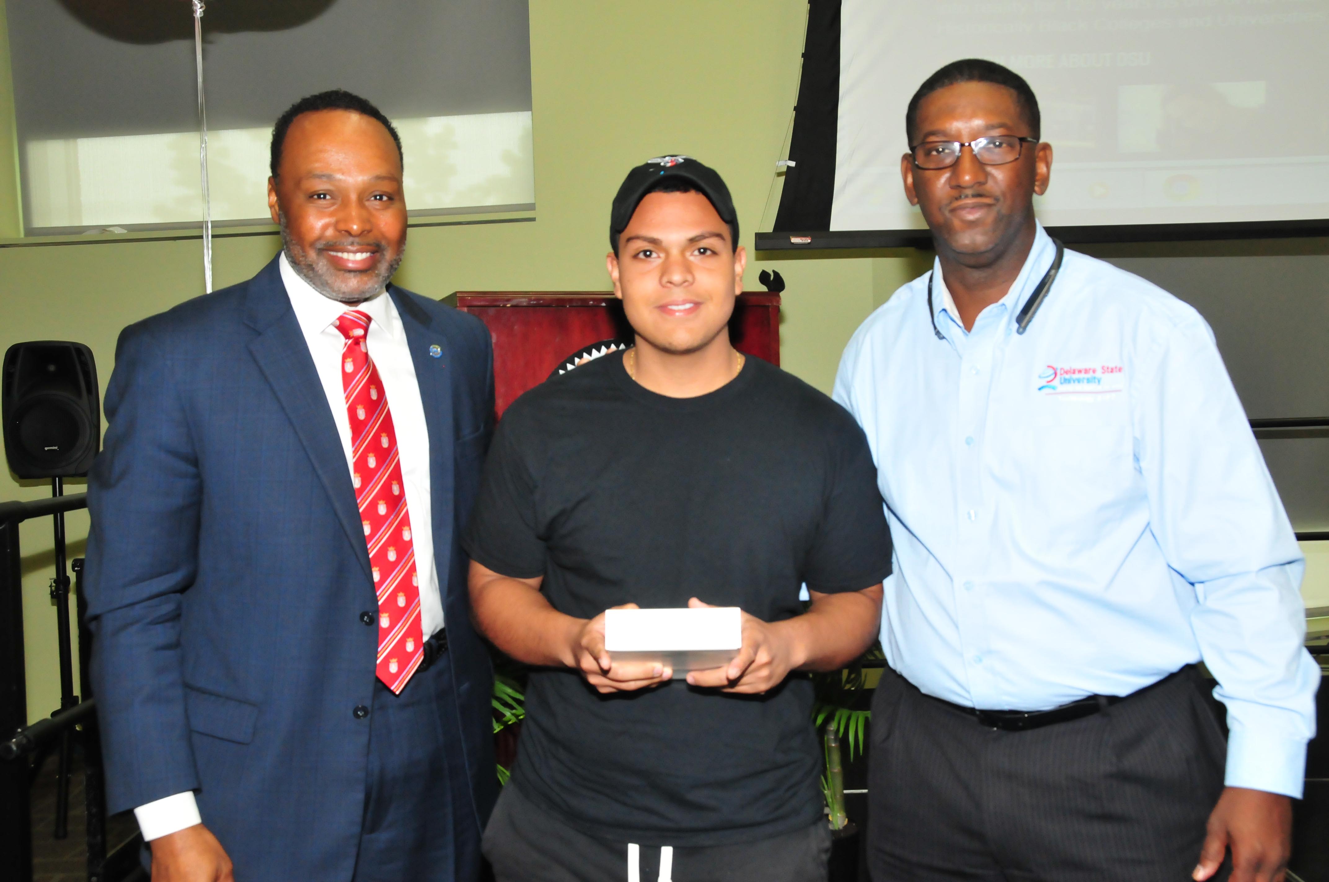 Kevin Coque Alarcon, a freshman mass communications major (center), won a digital drawing and took home an iPad Mini. Standing with him are keynote speaker James Collins (l) and DSU CIO Darrell McMillon.