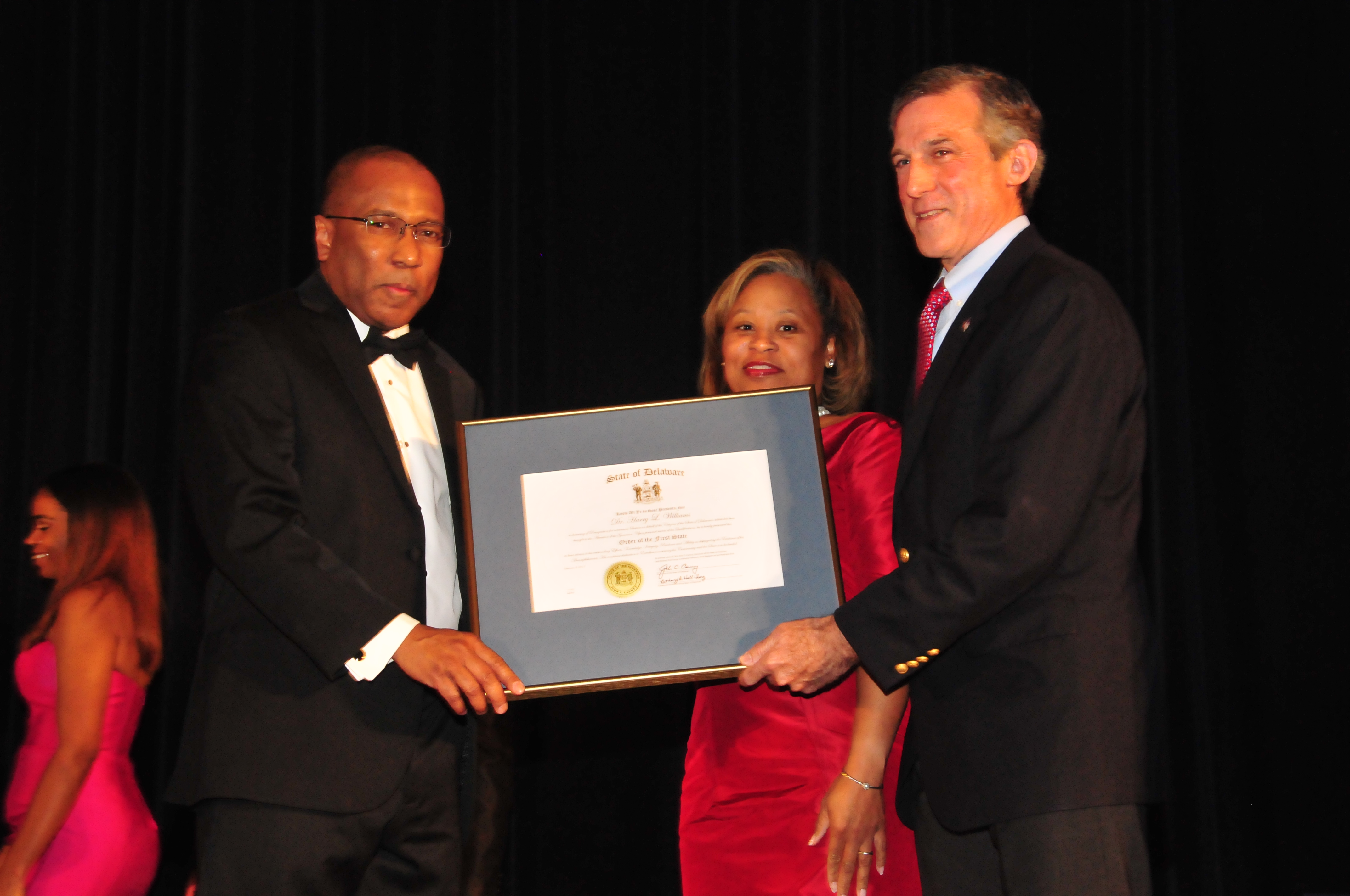 Dr. Harry L. Williams (l), joined by his wife Dr. Robin Williams, receives the Order of the First State from Delaware Gov. John Carney during the Dec. 9 President's Scholarship Ball.