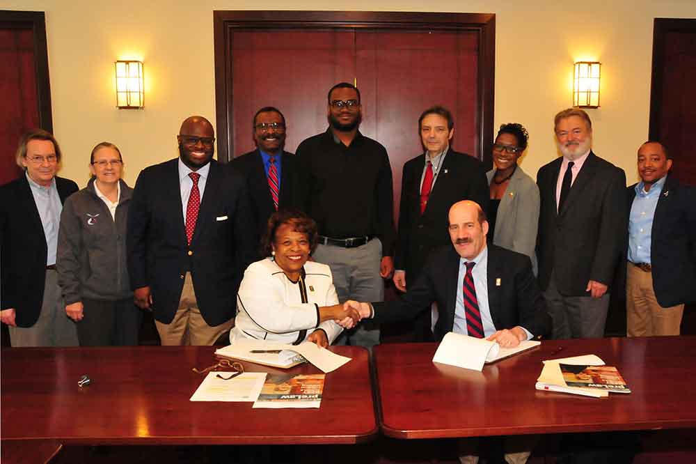 DSU Acting President Wilma Mishoe shakes hands with Mitchell Hamline School of Law President Mark C. Gordon after signing an agreement. MHSL will provide DSU with several undergraduate online law courses at no cost to Del State.