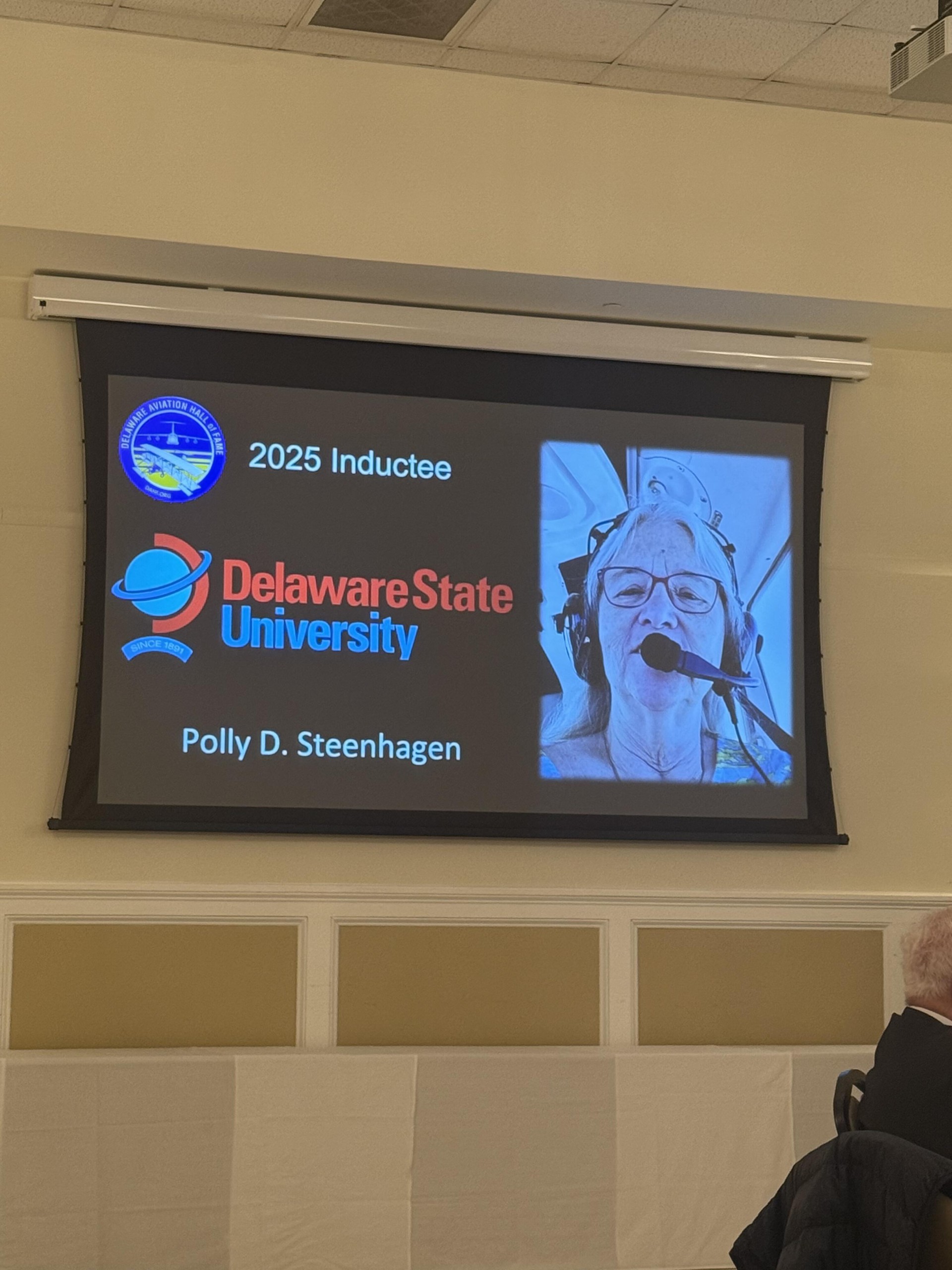 A ceremony slide announcing Dr. Polly Steenhagen as a 2025 Delaware Aviation Hall of Fame inductee.